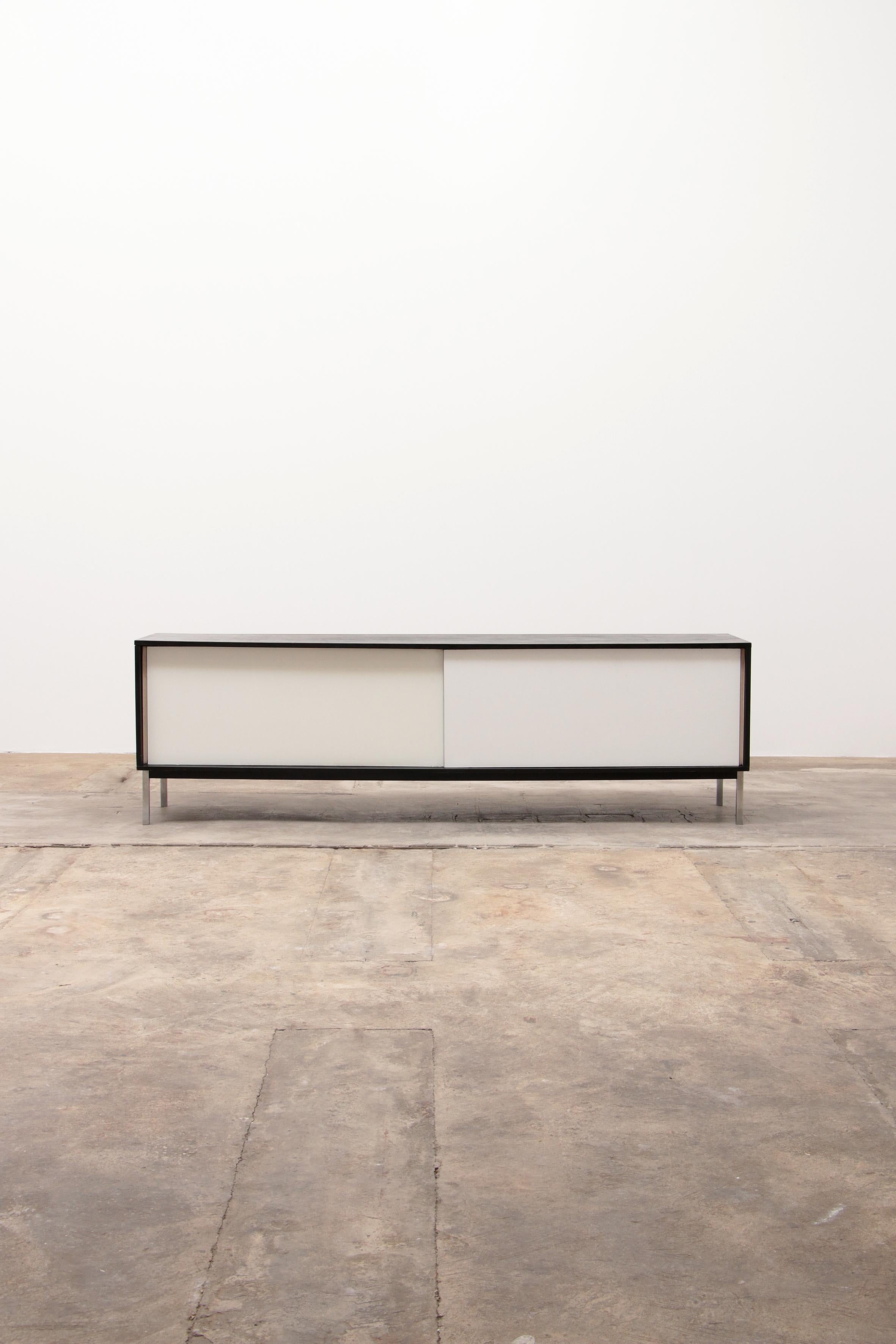 This minimalist and modernist sideboard, model KW85, was designed by Martin Visser for 't Spectrum in the Netherlands in 1965.

It is made of black lacquered veneer and has white sliding doors and a hidden drawer, all on a metal base. Right