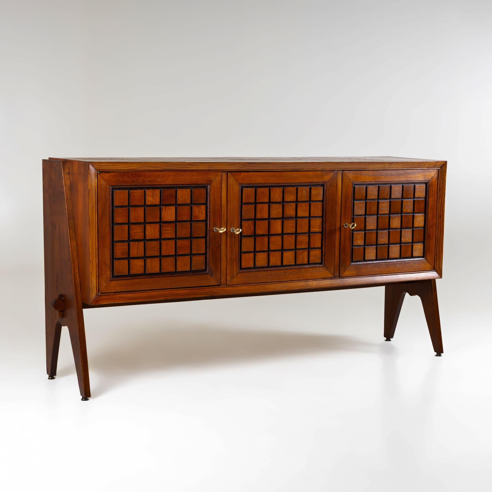 Dreitüriges Sideboard aus mittelbraun gebeiztem Holz, wahrscheinlich italienischer Herkunft, um 1970. Die Vorderseite weist ein markantes Gitterrelief auf, das dem Stück ein kühnes, grafisches Aussehen verleiht. Er steht auf spitz zulaufenden,