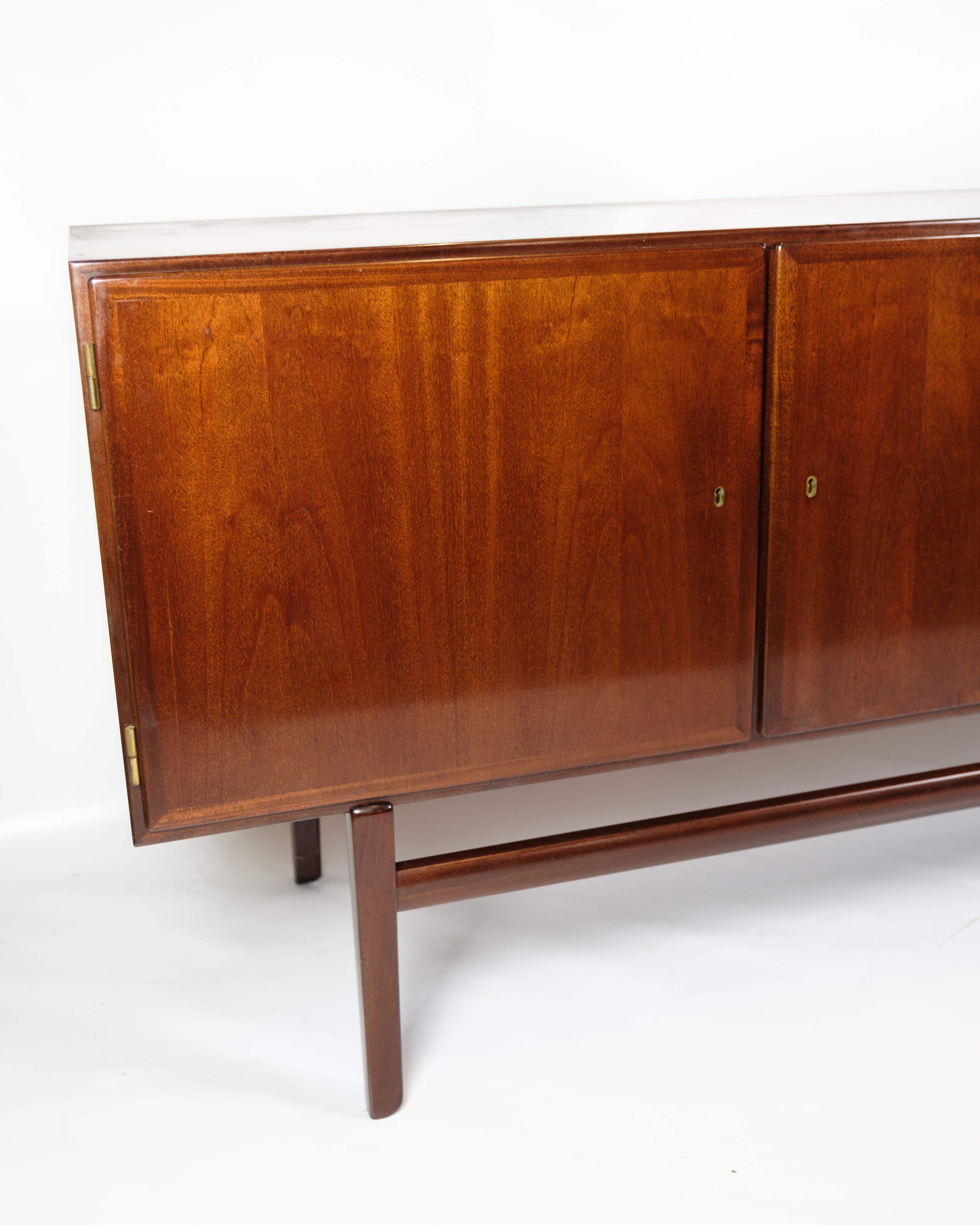Mahogany sideboard, designed by Ole Wanscher and manufactured by P. Jeppesen in the 1960s. The sideboard has three doors on the front, which open up to spacious storage compartments with shelves on both sides and two drawers in the middle, ideal for