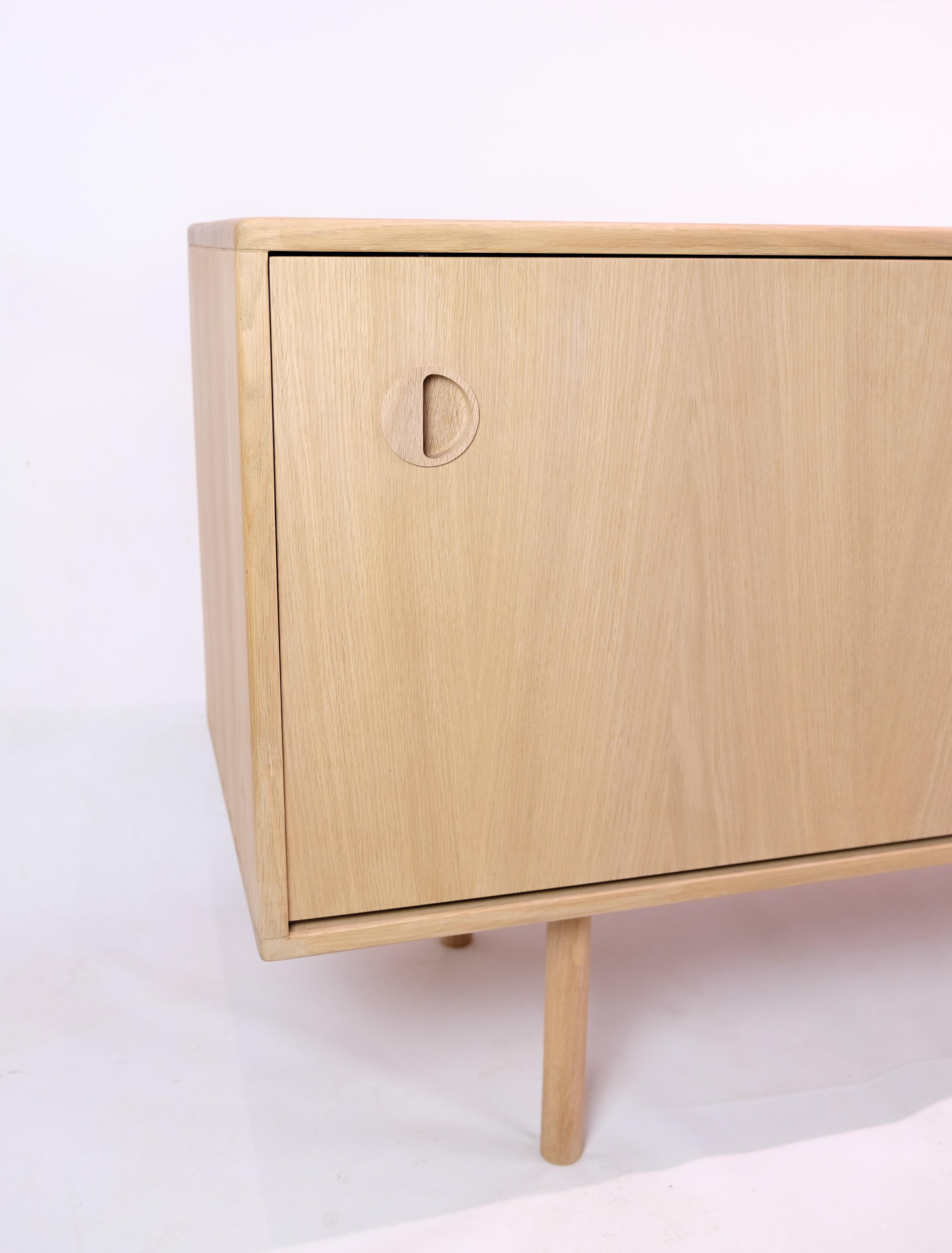 Beautiful oak sideboard of light soap-treated oak with sliding doors and stylish handles by Kurt Østervig from the 1970s. The sideboard has internal shelves and round legs.

Dimensions: H:75cm W:180cm D:46cm