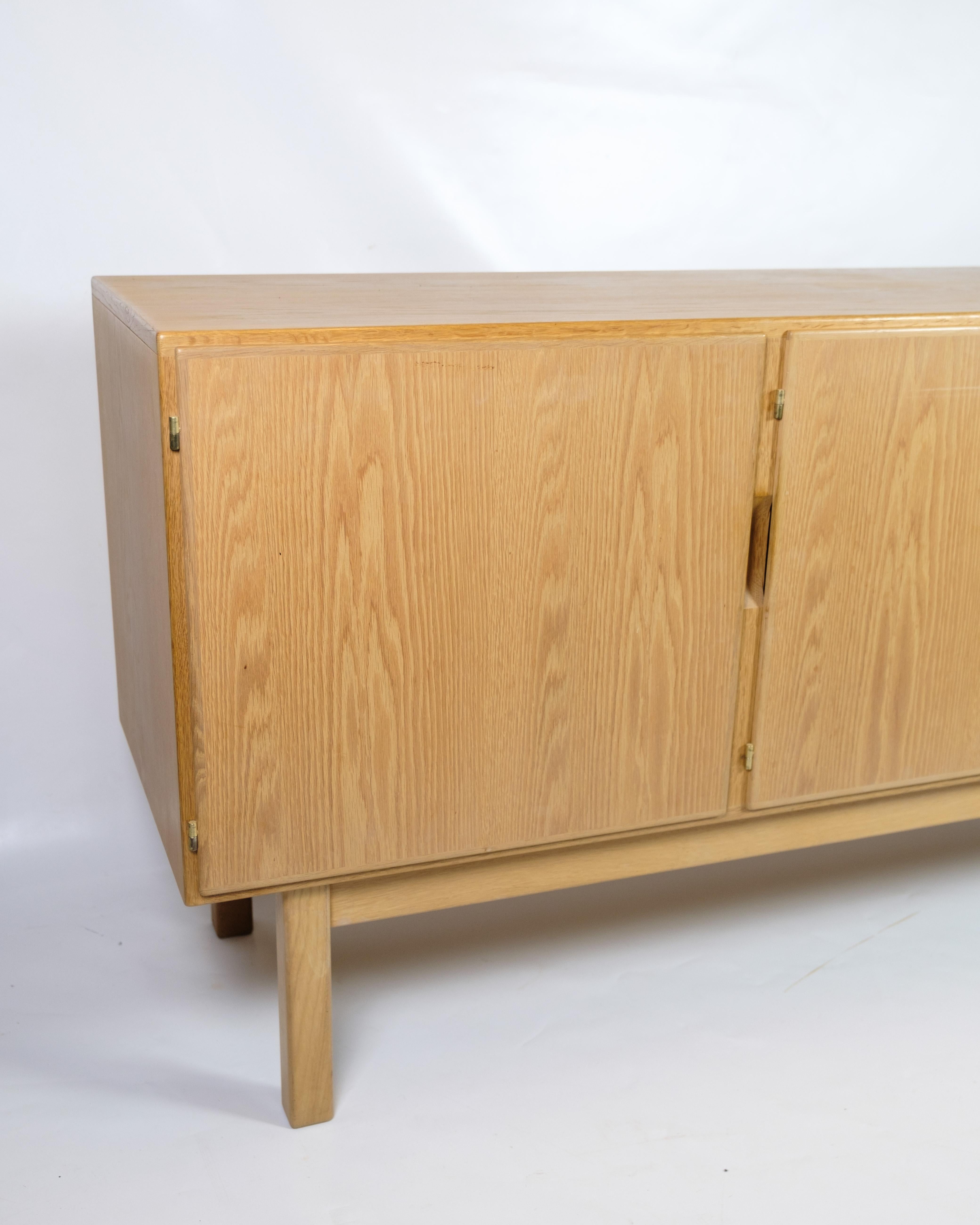 Sideboard aus heller Eiche aus den 1960er Jahren, hergestellt im dänischen Design. Das Sideboard hat drei Türen, die sich zu geräumigen Ablagefächern mit Einlegeböden und drei ausziehbaren Schubladen öffnen lassen, ideal für die Aufbewahrung