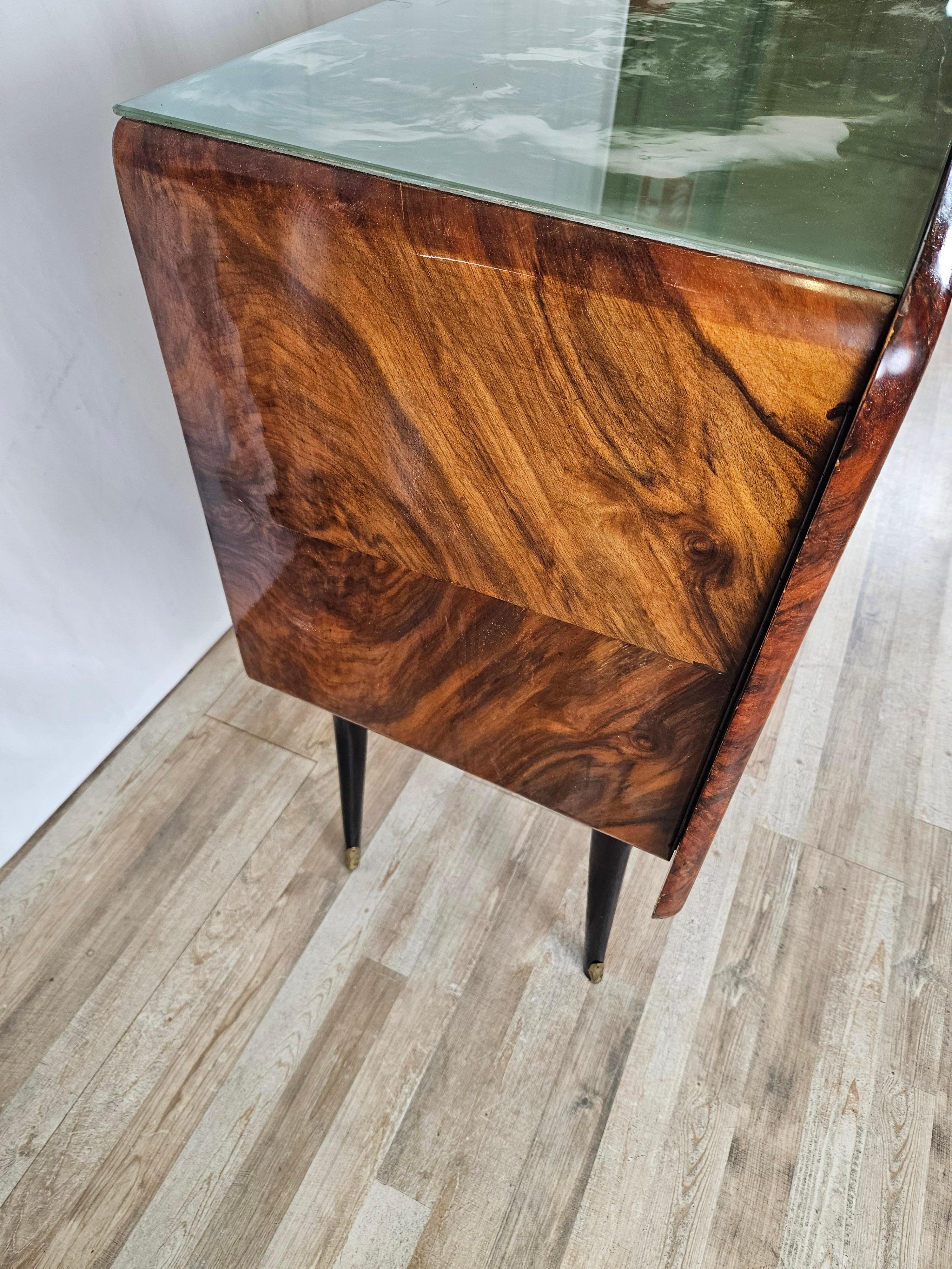 Italian-made mid-century sideboard, fully wood-paneled with three doors and green marbled glass top.

The cabinet is presented with brass handles and foot braces, and in the center is a door covered with processed glass and satin-finished on the