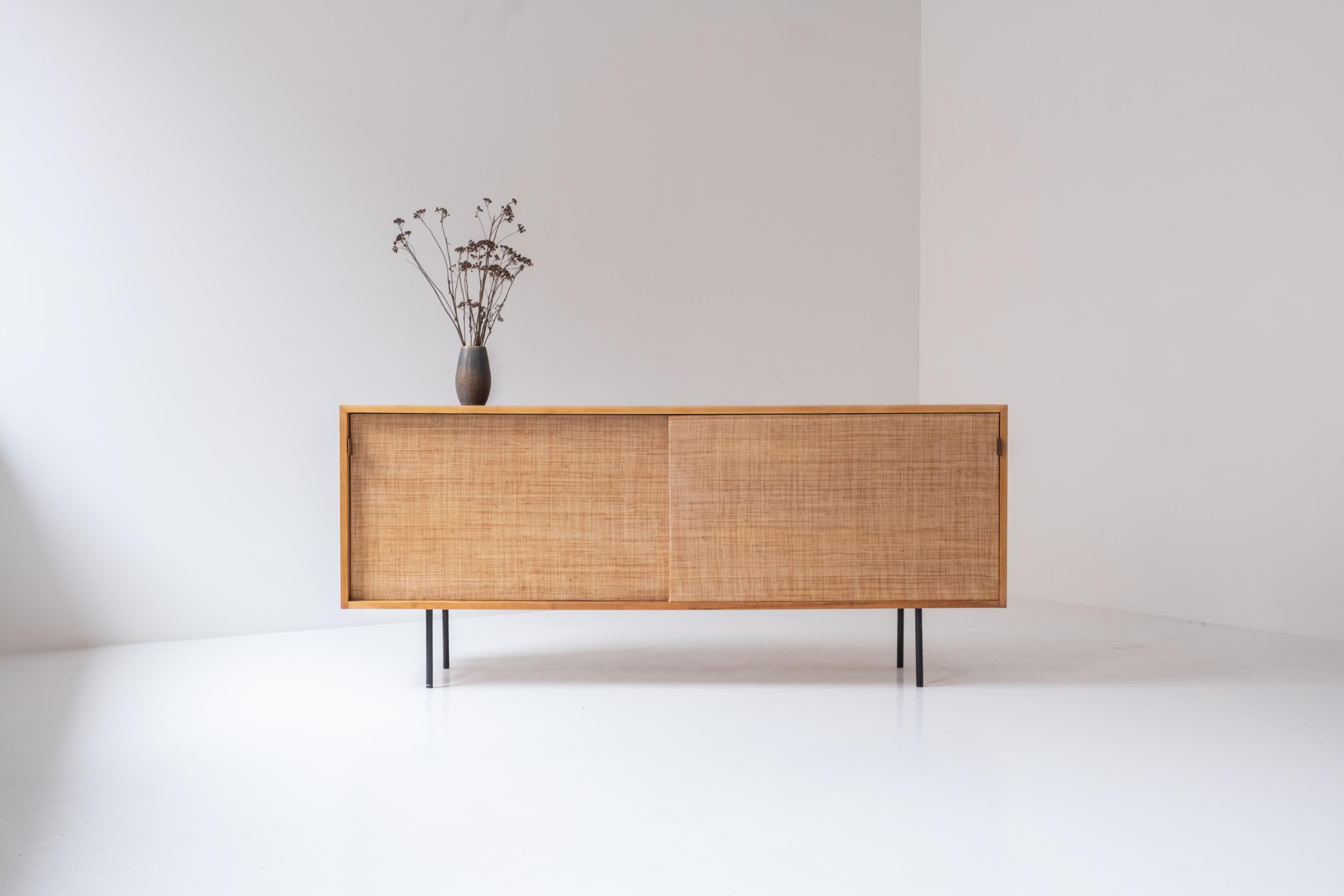 Lovely sideboard by Florence Knoll for Knoll international, USA 1950s. This sideboard is model 116 and is made out of ash wood. The two seagrass sliding doors features patinated cognac leather handles covering a maple interior on the inside. This