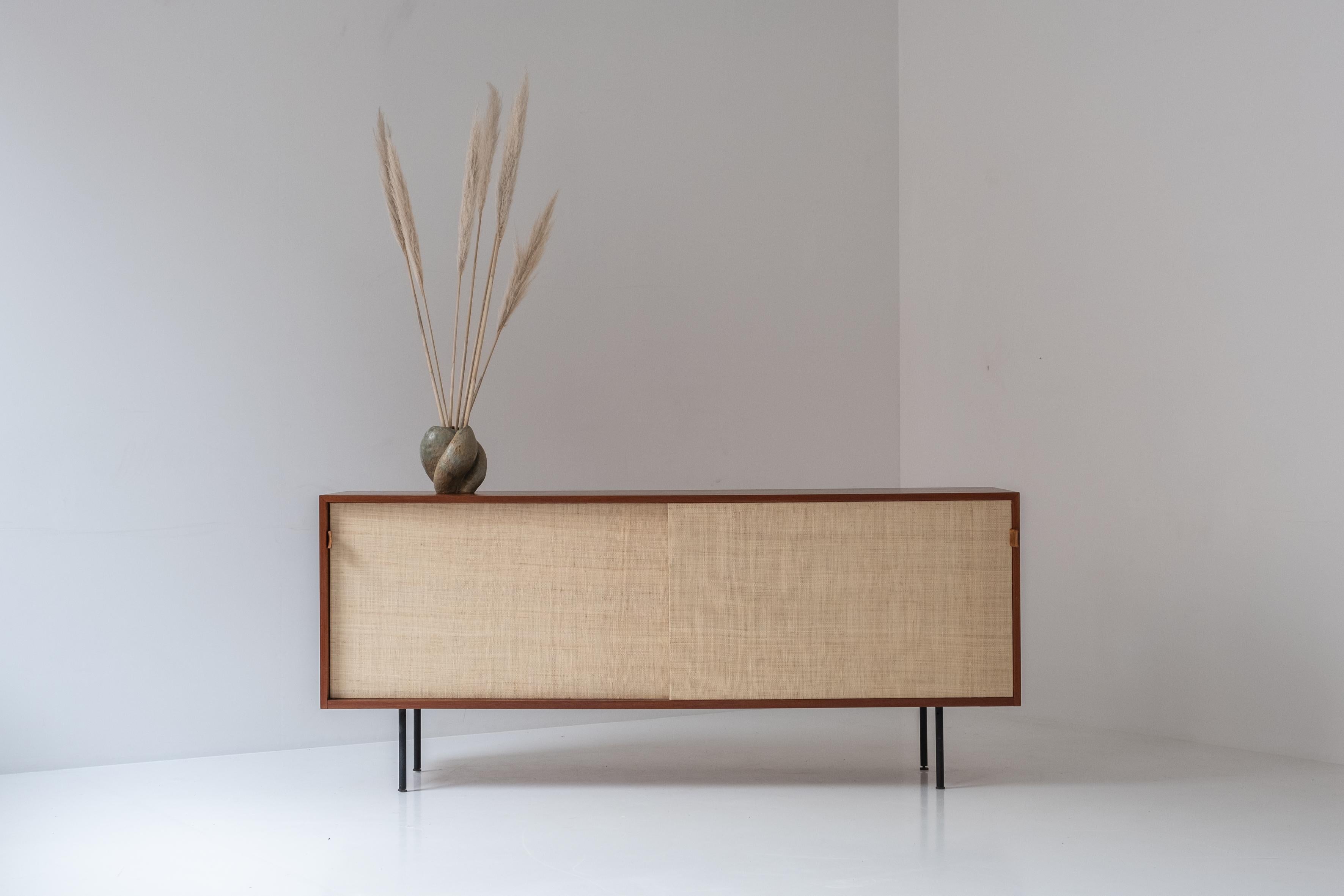 Lovely sideboard by Florence Knoll for Knoll international, USA 1950s. This sideboard is model 116 and is made out of teak wood. The two seagrass sliding doors features patinated cognac leather handles covering a maple interior on the inside. This