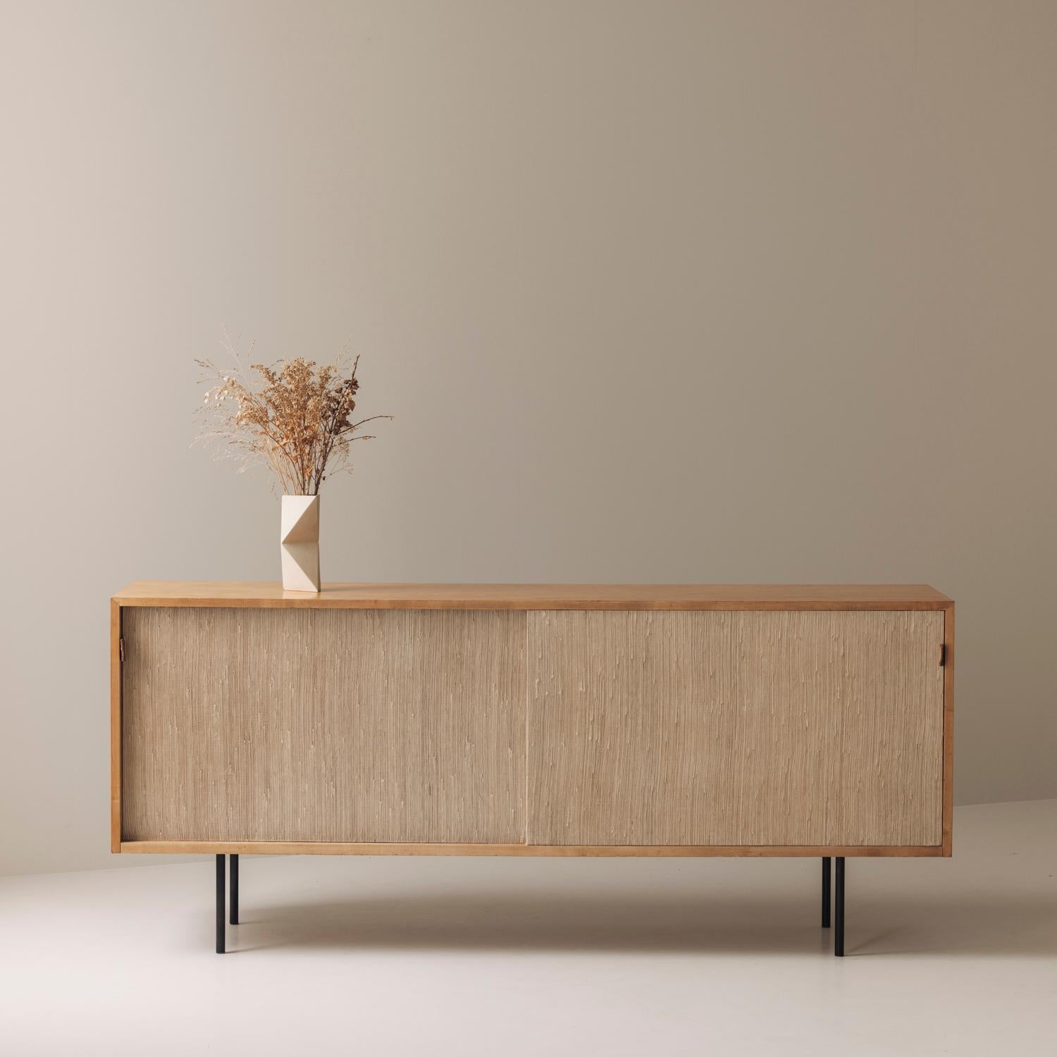 An exceptional example of mid-century modern design, this Model 116 sideboard was designed by Florence Knoll for Knoll International in the 1950s. Made out from rich honey colored wood, it features two elegant seagrass sliding doors adorned with