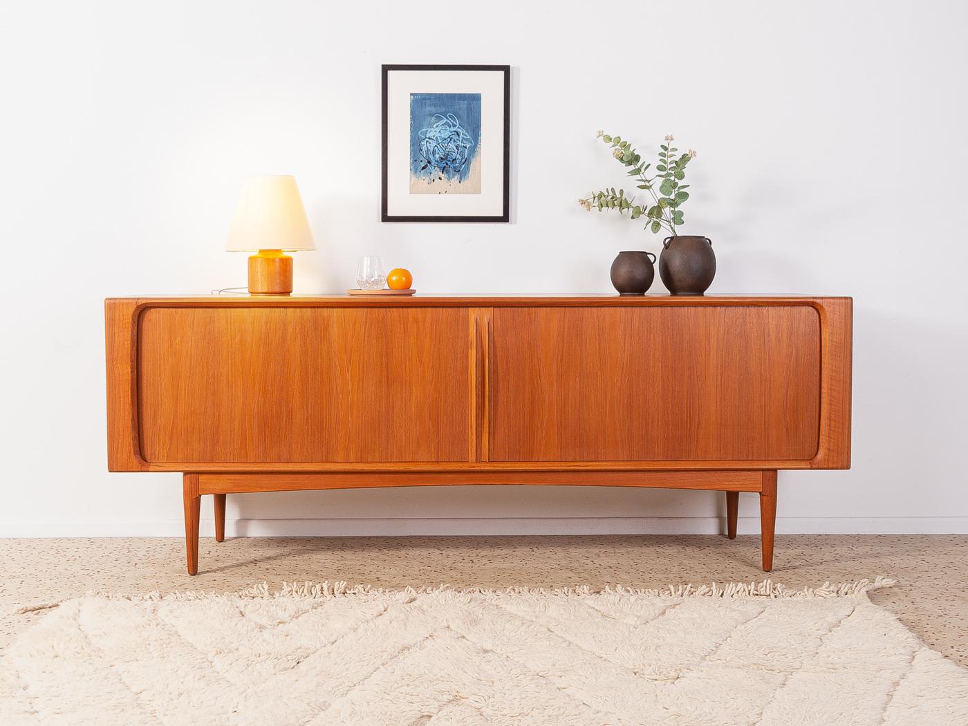 Sideboard 142 from the 1960s by Bernhard Pedersen & Søn. High-quality corpus in teak veneer with two tambour doors, three internal drawers, two shelves and tapered feet.

Quality Features:
    accomplished design: perfect proportions and visible
