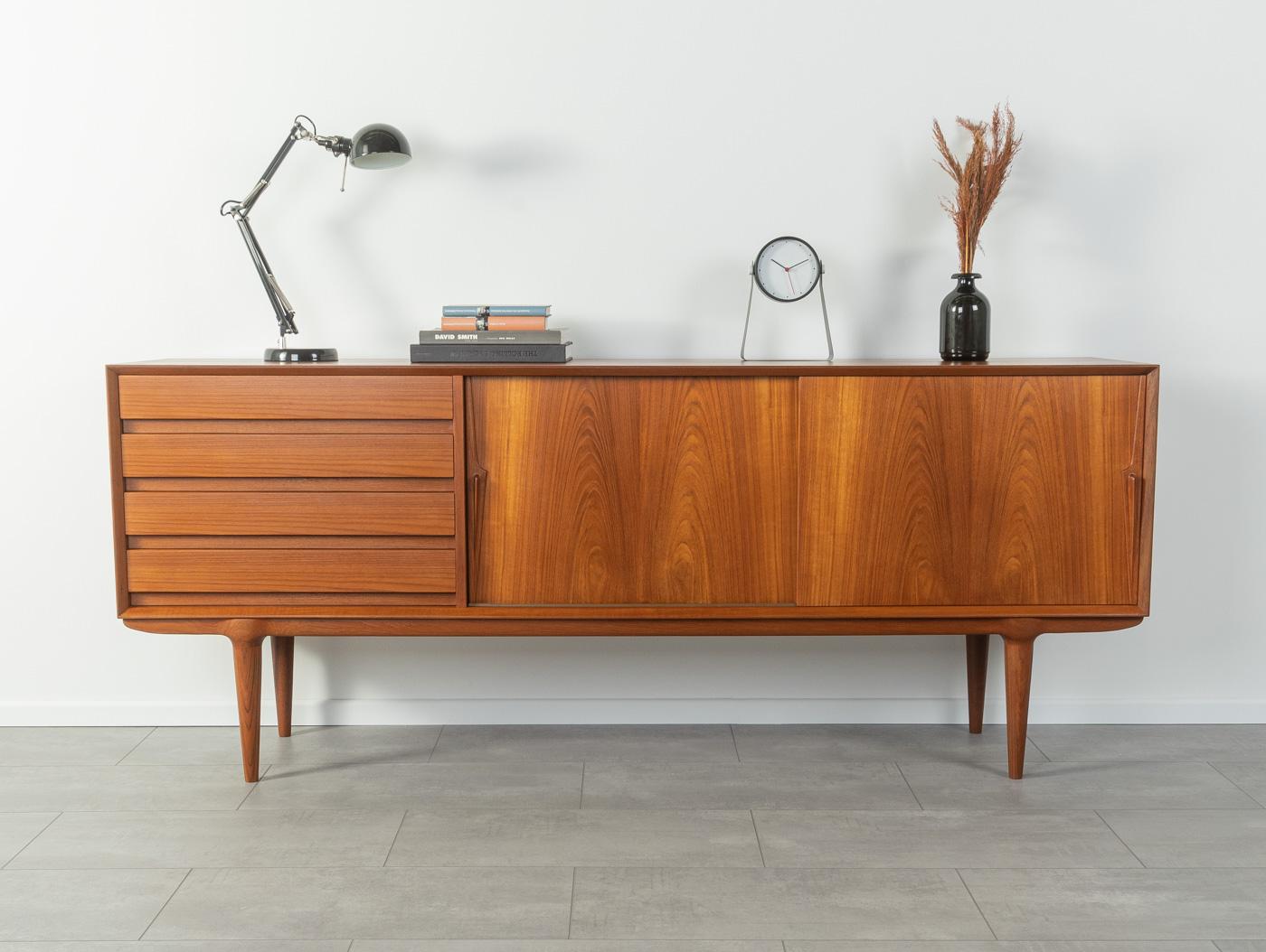 Filigree sideboard by Omann Jun., model 18. High-quality corpus in teak veneer with two sliding doors, an insert shelf, four drawers and cigar shaped feet.
Quality features:

 Accomplished design: perfect proportions and visible attention to