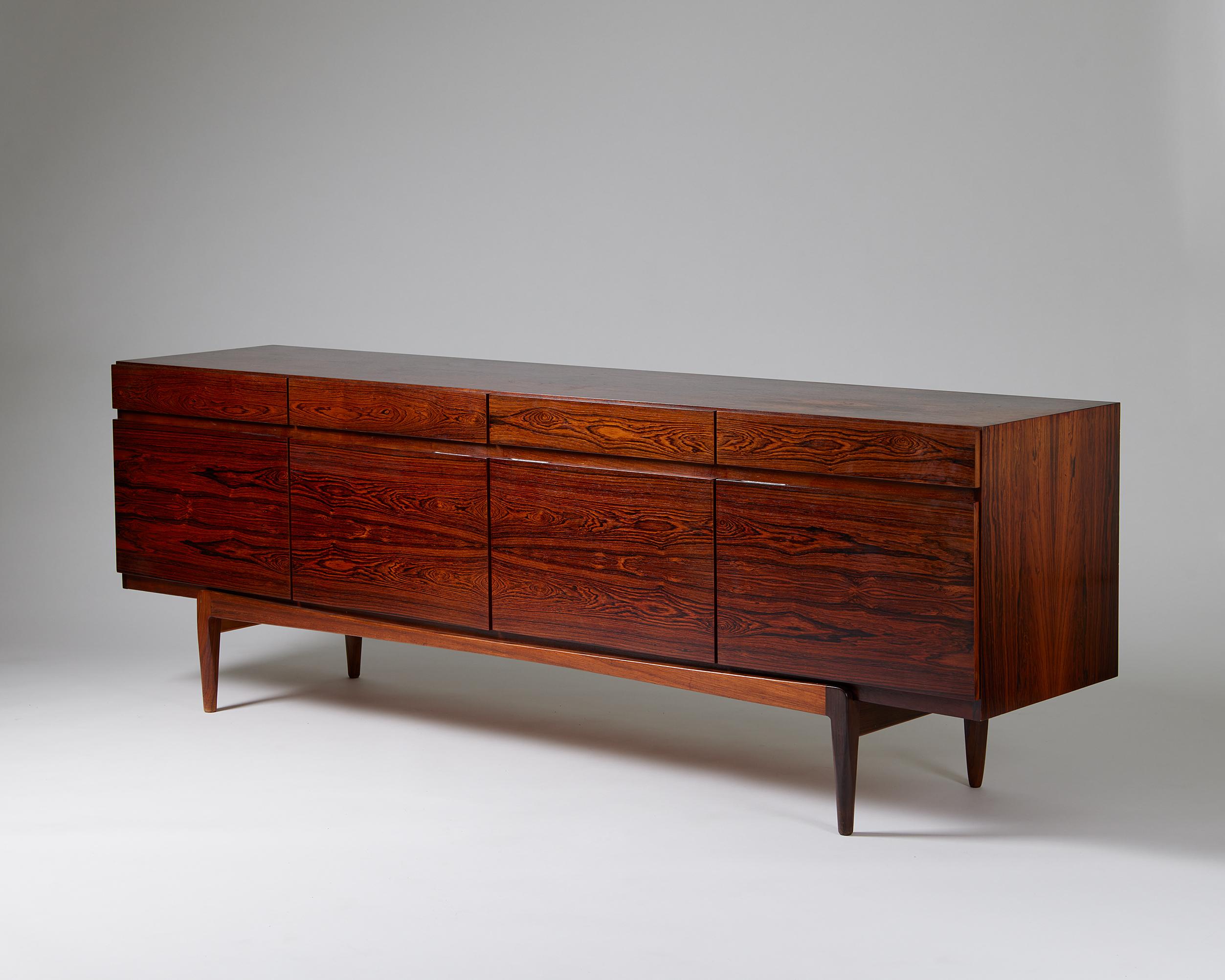The clean lines of Ib Kofod-Larsen’s model FA 66 in rosewood make it a notable Scandinavian mid-century collectable. Remarkably, it appears as if the elegant body balances on a separate cradle, but the base is in fact attached. Combining