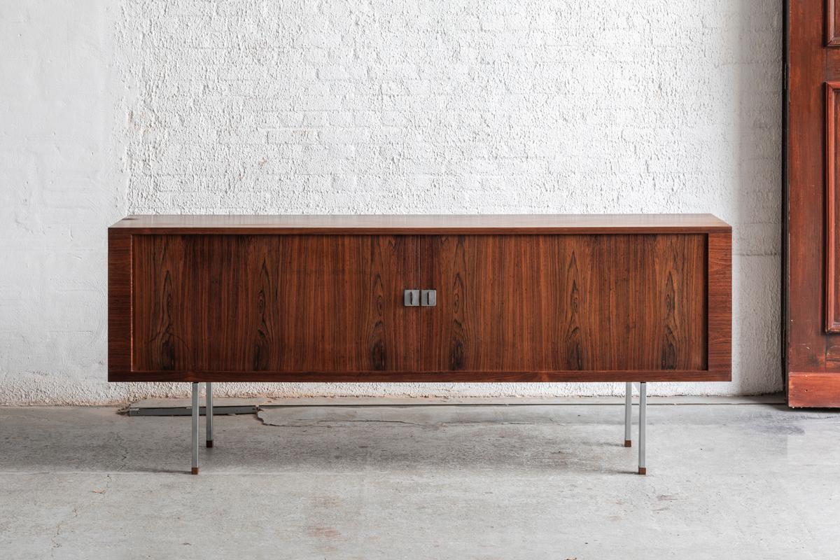Rare sideboard designed by Hans Wegner and produced by Ry Mobler in Denmark starting from 1962. This piece, made of rosewood veneer on the outside and oak on the inside, shows great craftmanship. The tambour doors, beautiful grained veneer panels