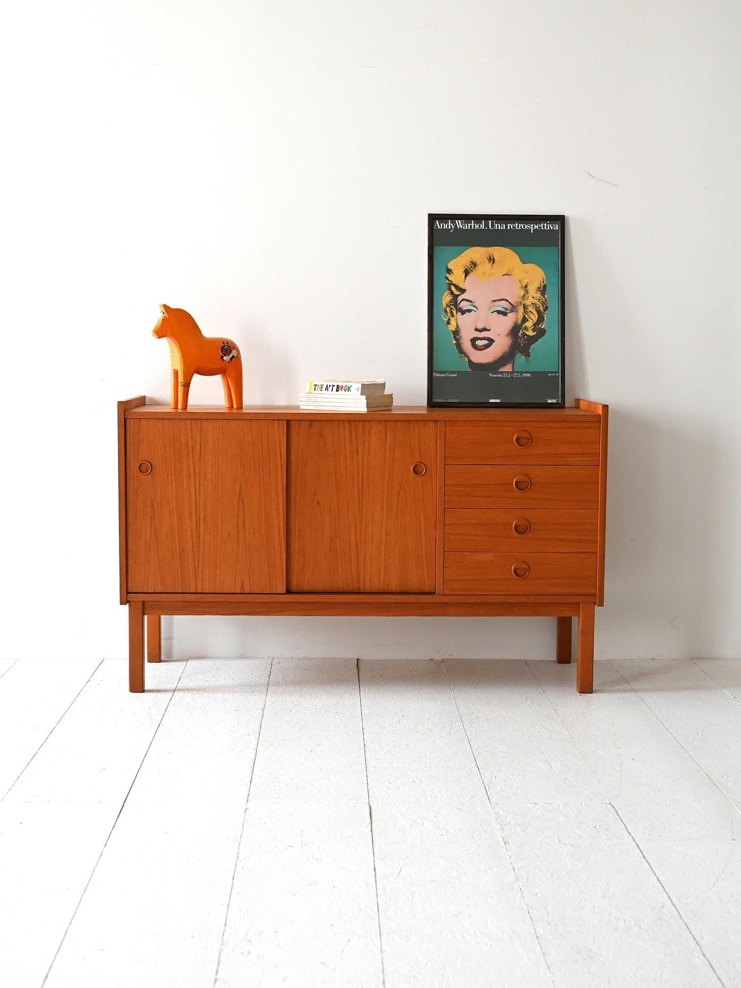 Mobile basso con ante scorrevoli e quattro cassetti, struttura lineare in legno chiaro e gambe squadrate.

Mobile sideboard in stile scandinavo risalente agli anni 50/60, realizzato in teak con finitura calda e uniforme. Presenta due ante