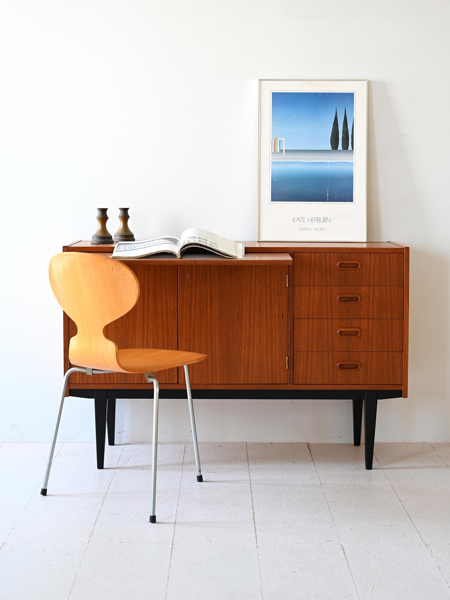 Mobile contenitore anni '60 in teak con piano estraibile e gambe dipinte di nero. 

Le dimensioni contenute permettono a questo sideboard di essere inserito anche in piccoli spazi. Grazie alla possibilità di estrarre il piano, può essere utilizzato,