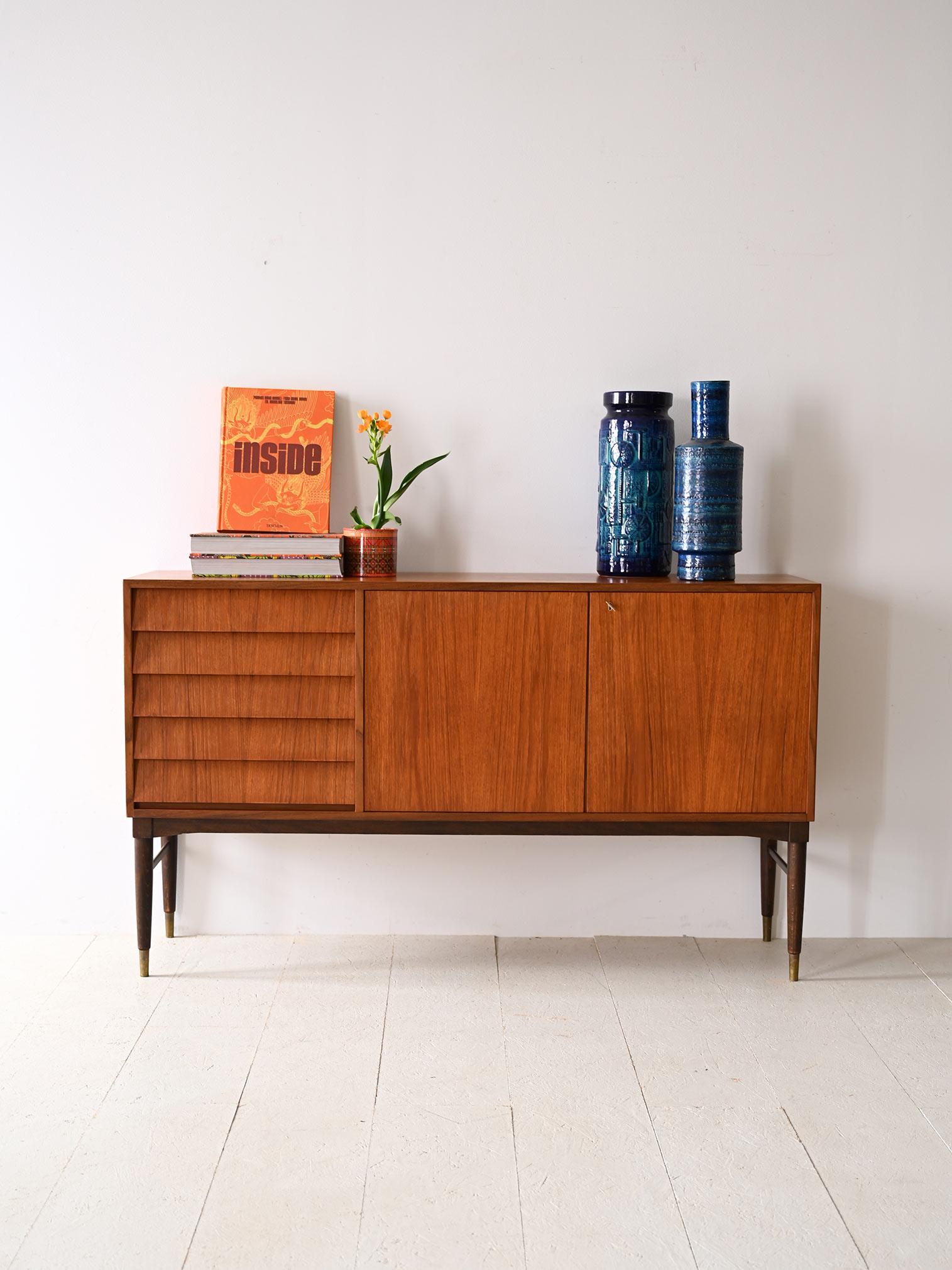 Credenza anni '60 in teak con ante e cassetti.

Doté d'une silhouette élégante et légère, ce vêtement est destiné à devenir le point focal de tout environnement, en ajoutant un élément de style en un rien de temps.
Les poutres longues en cuir,