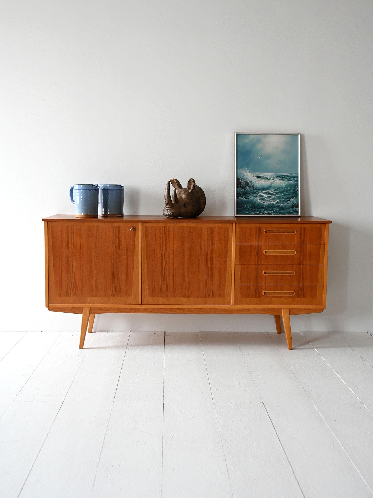 Teak sideboard with four drawers, hinged doors and double wood veneer in contrasting tones.

Produced by Ulferts in the late 1950s, this Scandinavian teak sideboard features an interesting double-wood veneer with slight color variations. The two