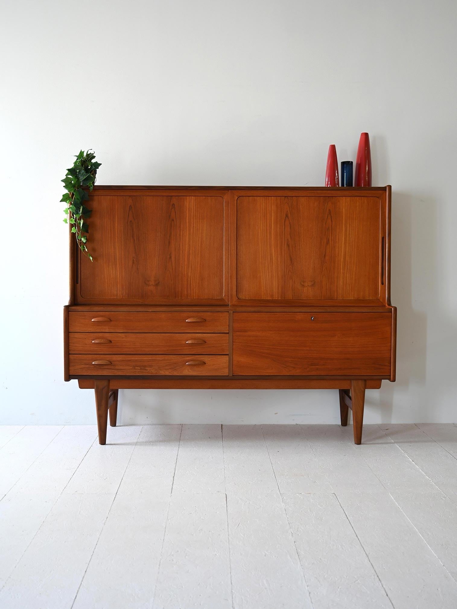Vintage teak sideboard with sliding doors, drawers and interior compartments with modular shelves.

Original Scandinavian sideboard from the 1960s made of teak. Structure with sliding doors, four central drawers and compartments with adjustable