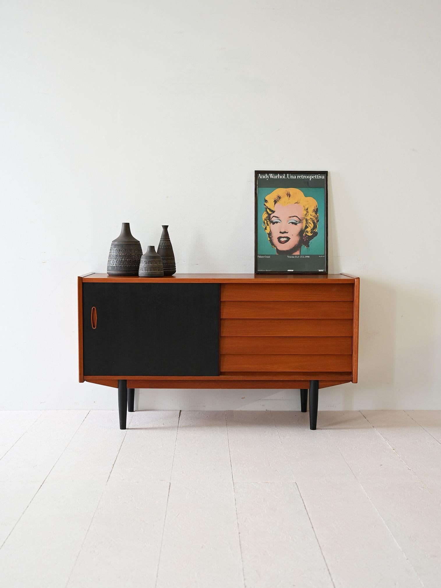 1950s/60s teak sideboard with black sliding door, front drawers and matching feet. Clean and essential design.

Scandinavian sideboard by Hugo Troeds, made of teak with a stylish contrasting black sliding door. The linear structure is enhanced by