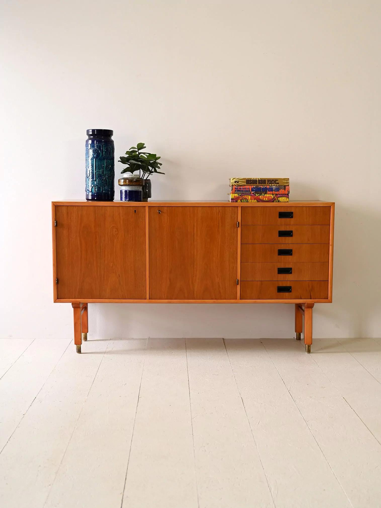 Original Scandinavian teak sideboard. 

It features five drawers and hinged doors, each with a lock, this piece of furniture boasts Scandinavian design with a touch of minimalism and aesthetic cleanliness. Sculpted handles with a darker brown color