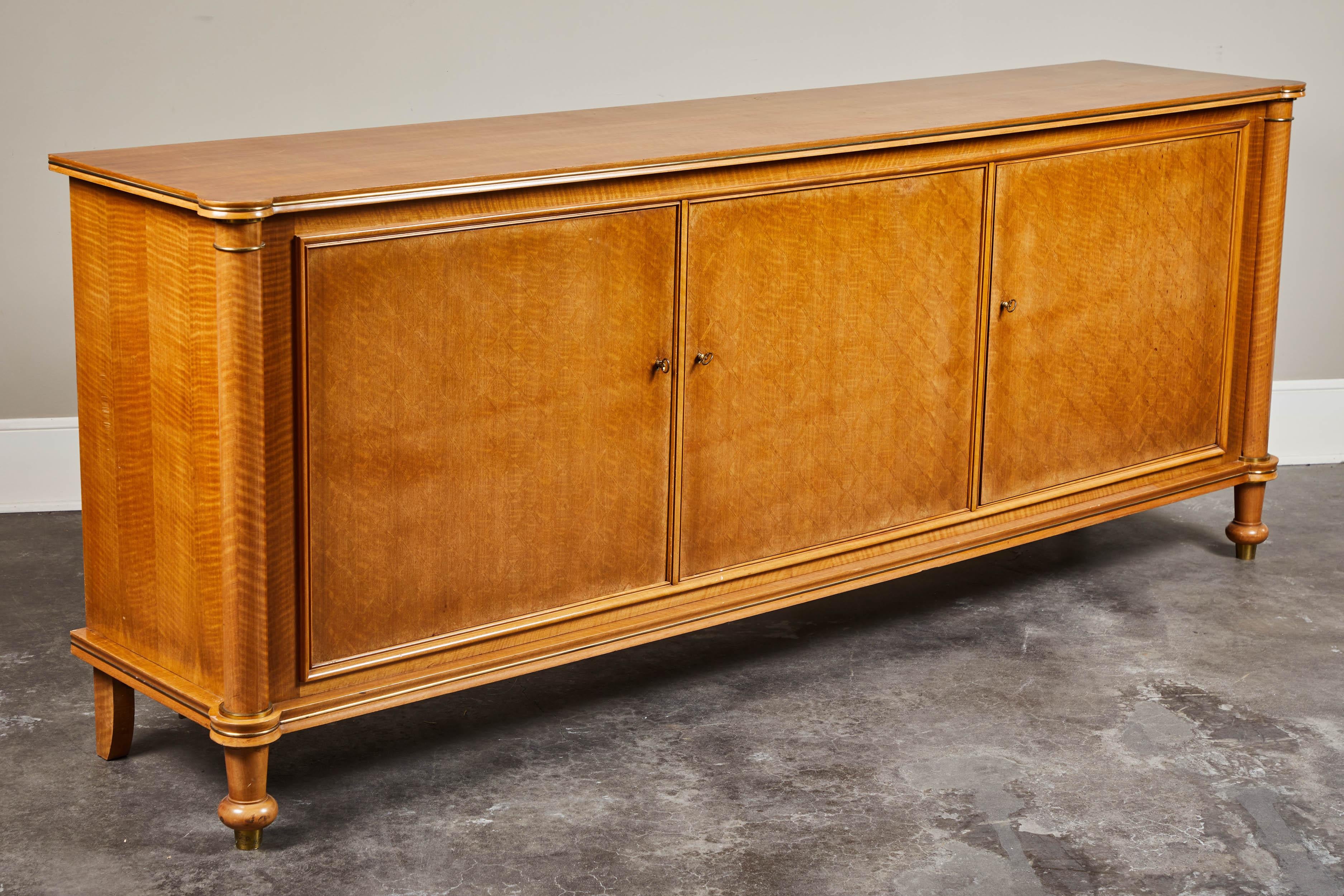 A sideboard signed and dated by the renowned Jules Leleu. Figured French Walnut on oak body, with three doors and two small drawers at centre interior. Features brass detailing throughout and impeccable attention to detail. Dated June, 1955, Paris.
