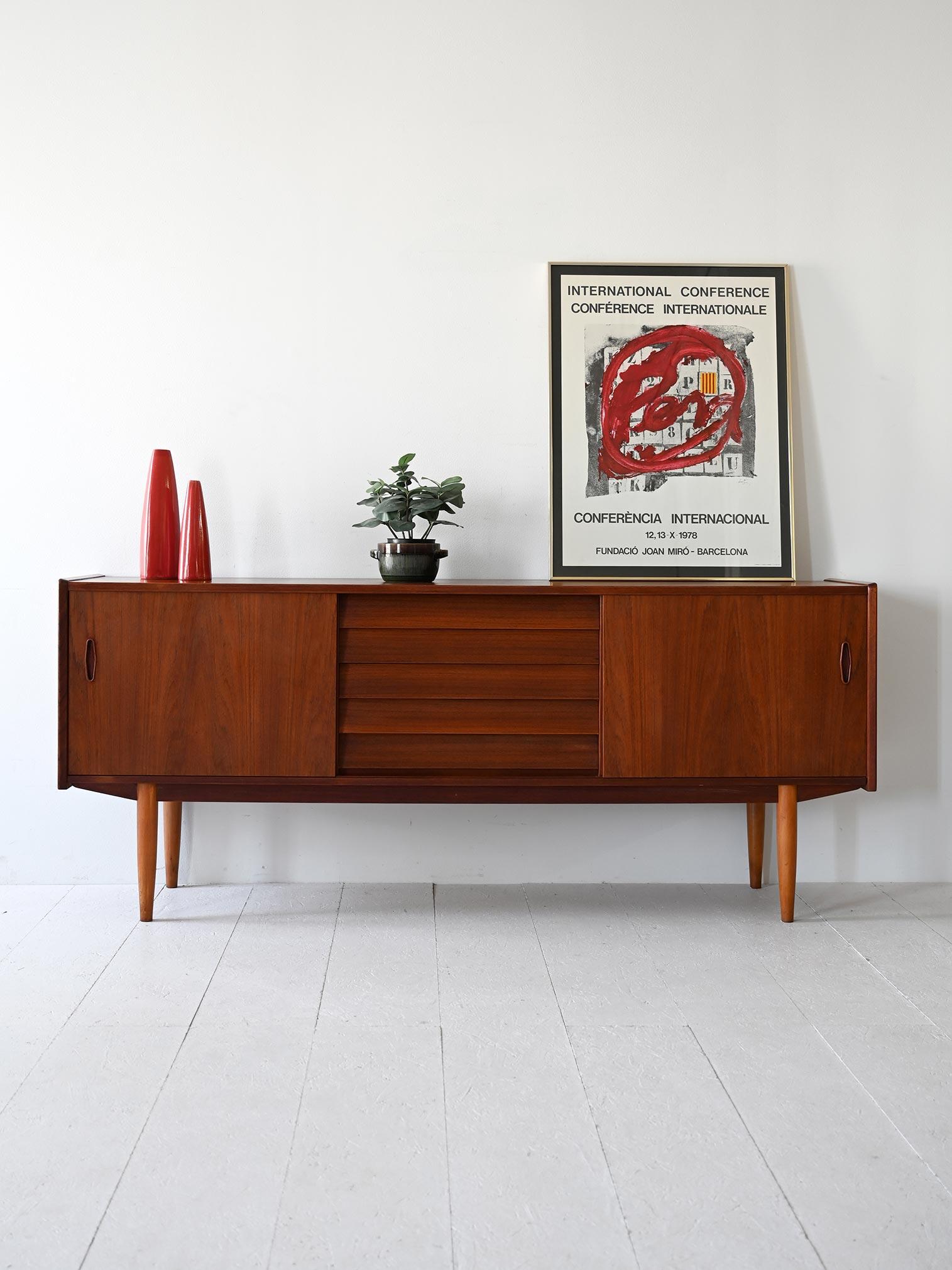 Credenza Trio di Nils Jonsson per Hugo Troeds, realizzata in Svezia negli anni '60. Costituita da cinque cassetti e due ante scorrevoli dotate di mensola. 

La struttura in teak e le linee moderne lo rendono un sideboard adatto anche ad ambienti
