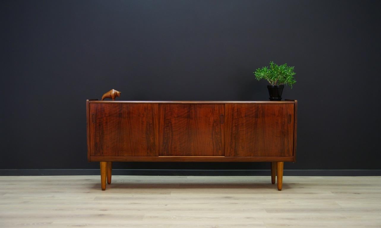 Unparalleled, stylish sideboard from 1960s-1970s. Excellent Danish design. Furniture veneered with rosewood. In the interior, behind the sliding doors, there are shelves and drawers made of rosewood. Preserved in good condition (small bruises and