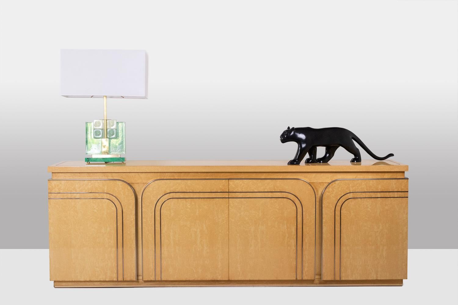 Credenza apribile sul davanti con 4 ante arrotondate, realizzata in legno di betulla e decorata con filetti di ottone.

Opera italiana realizzata negli anni '1970.

Dimensioni: H. H. 77,5 x L. 200 x P. 45 cm

Riferimento: LS6402987U