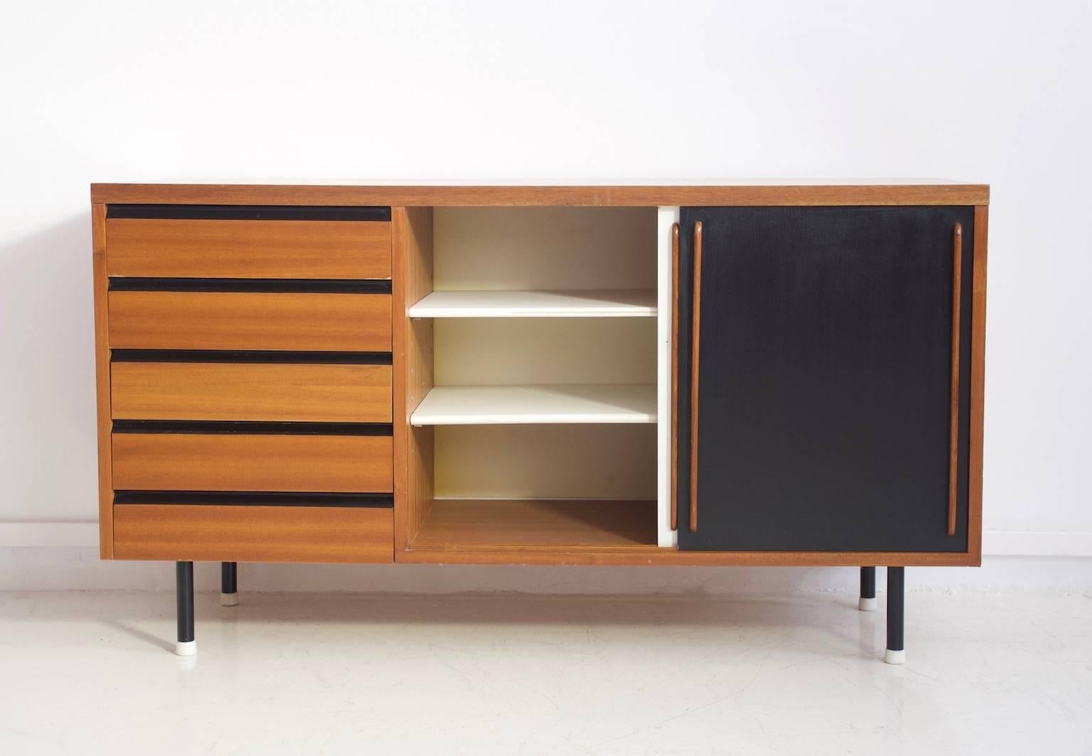 Teak sideboard with two black and white painted sliding doors in the style of Charlotte Perriand. Interior adjustable shelves and five drawers. Partly restored and later added metal legs.