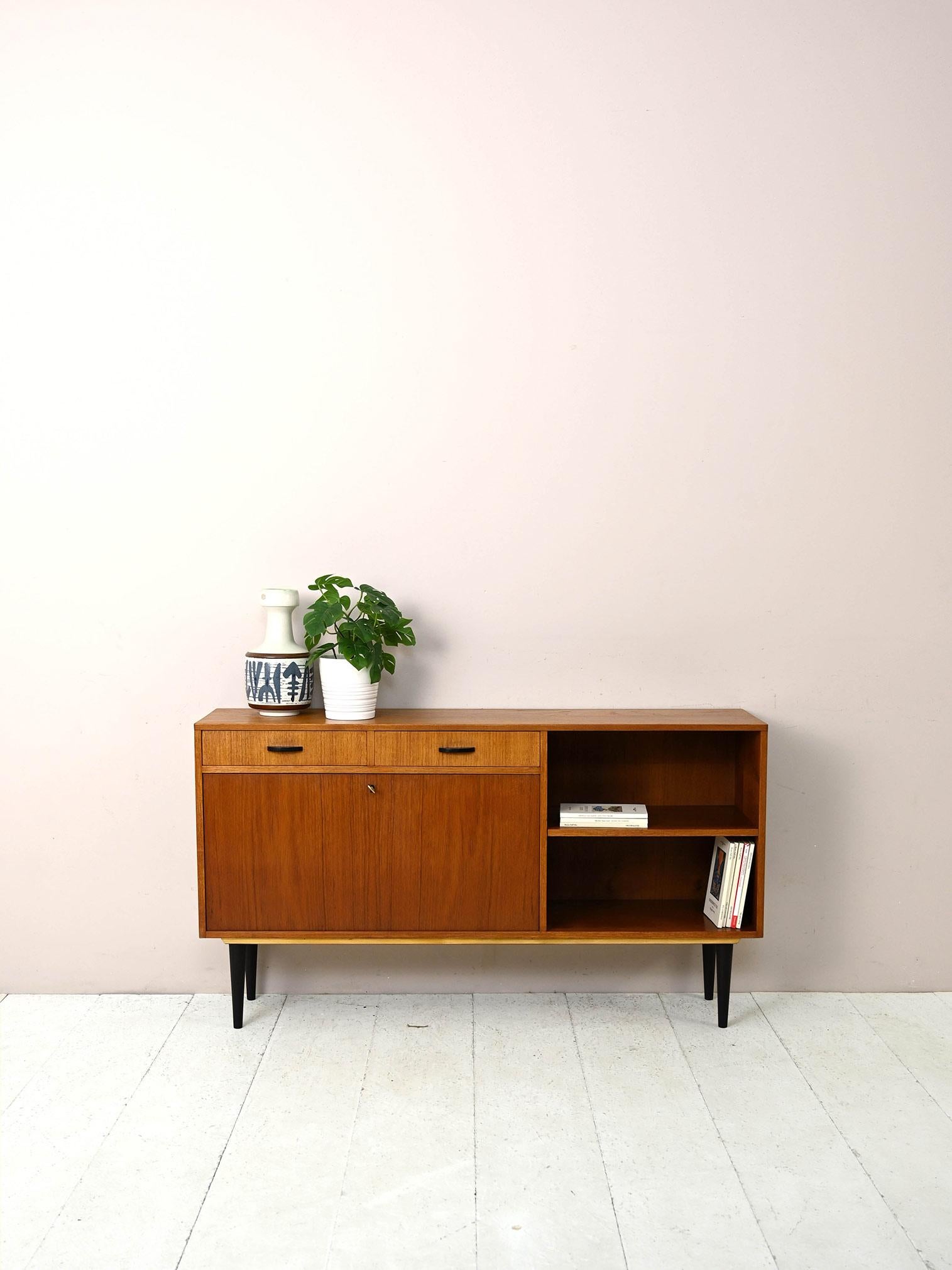 Console sideboard with bar compartment equipped with light.

This original 1960s Scandinavian piece of furniture is distinguished by its distinctive shape and the presence of a drop-down door concealing a shelf equipped with a light.
There are
