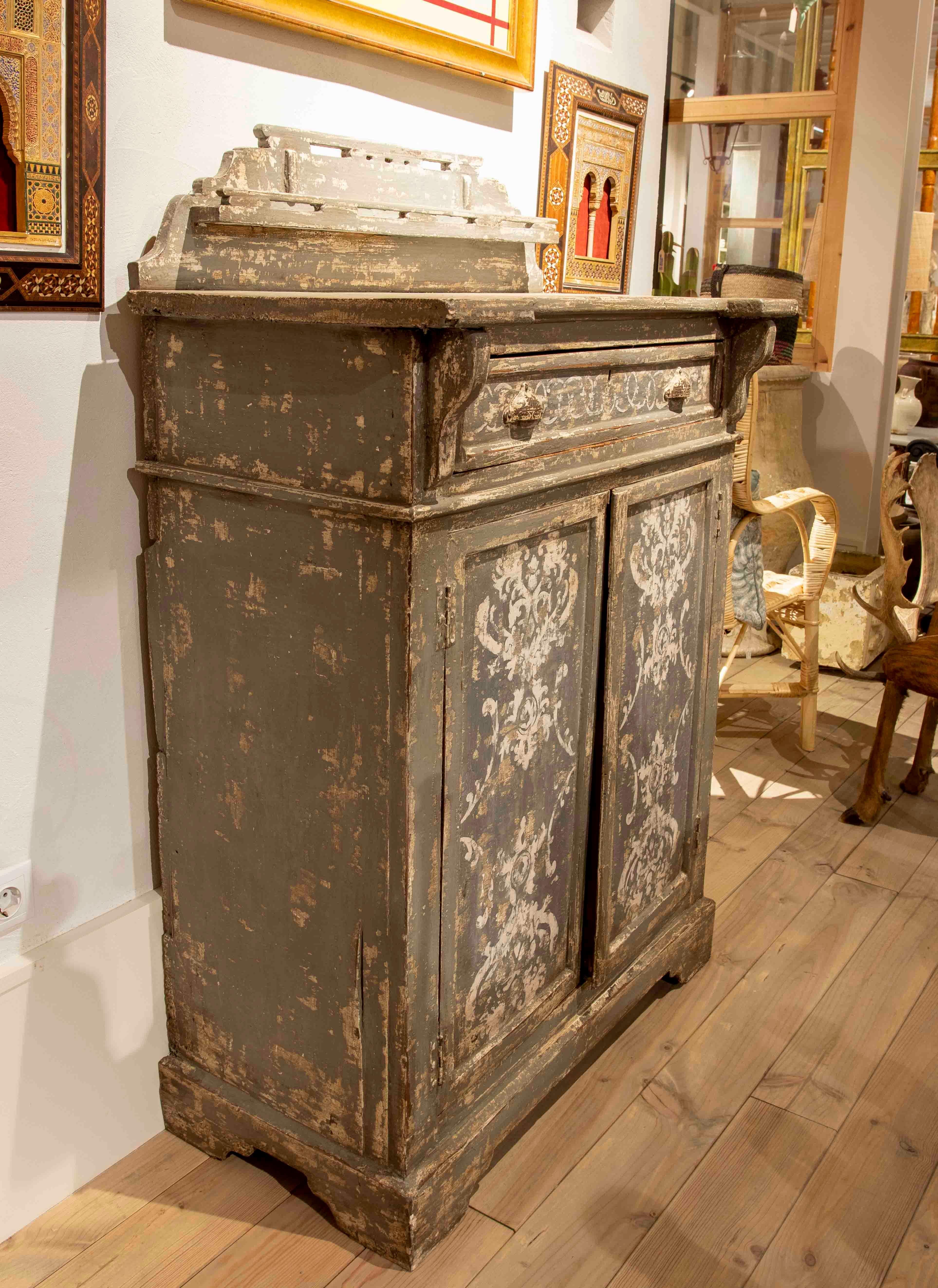 Credenza con ante e cassetti policromi nei toni del grigio e del bianco.