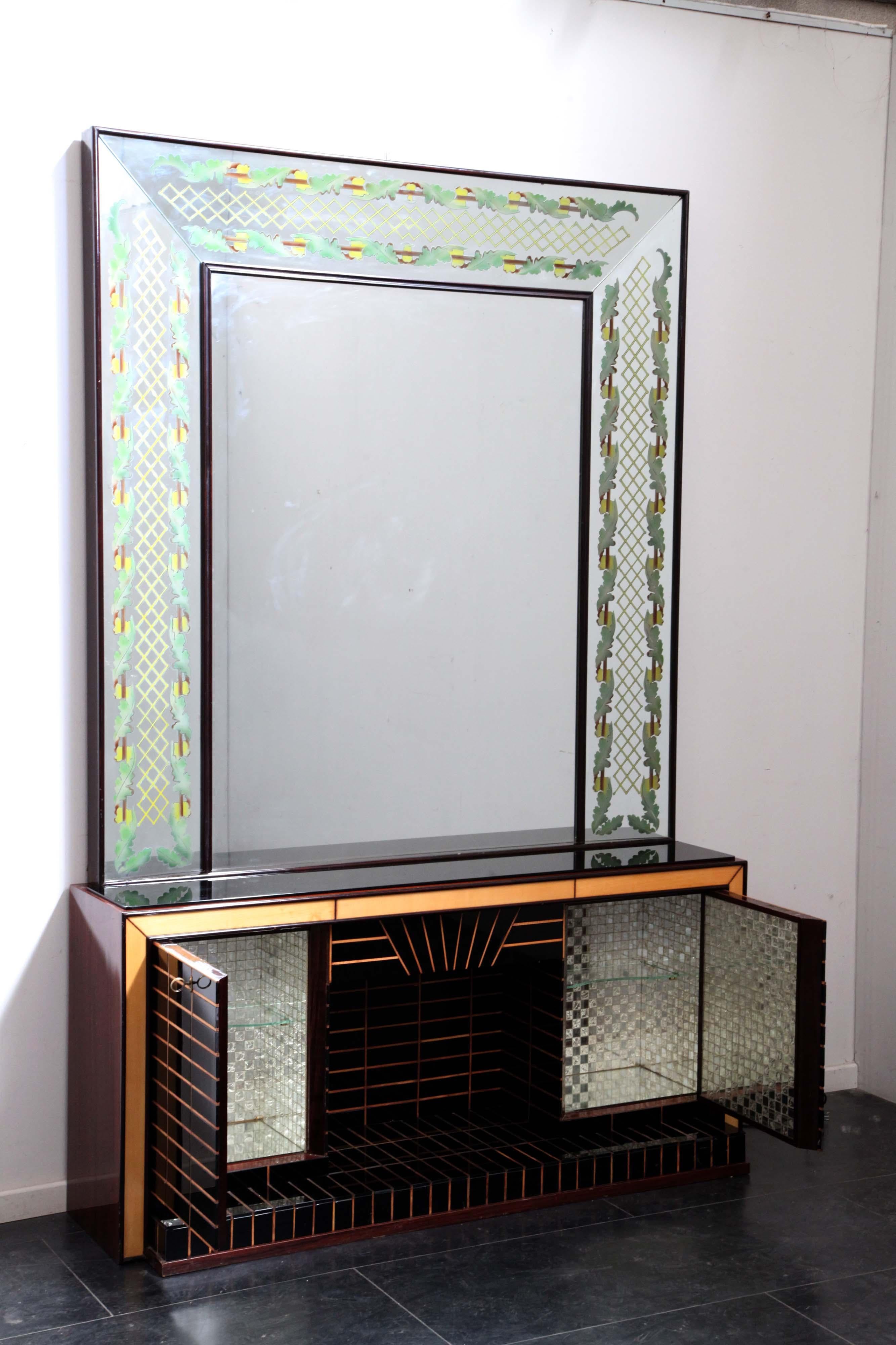 Chimney shaped sideboard, tessellated in black opaline glass outlined by maple profiles, the door closing at 45 degrees opens to a mirror mosaic interior, the top is in black opaline, the body in rosewood. 
The backlit mirror has a workmanship
