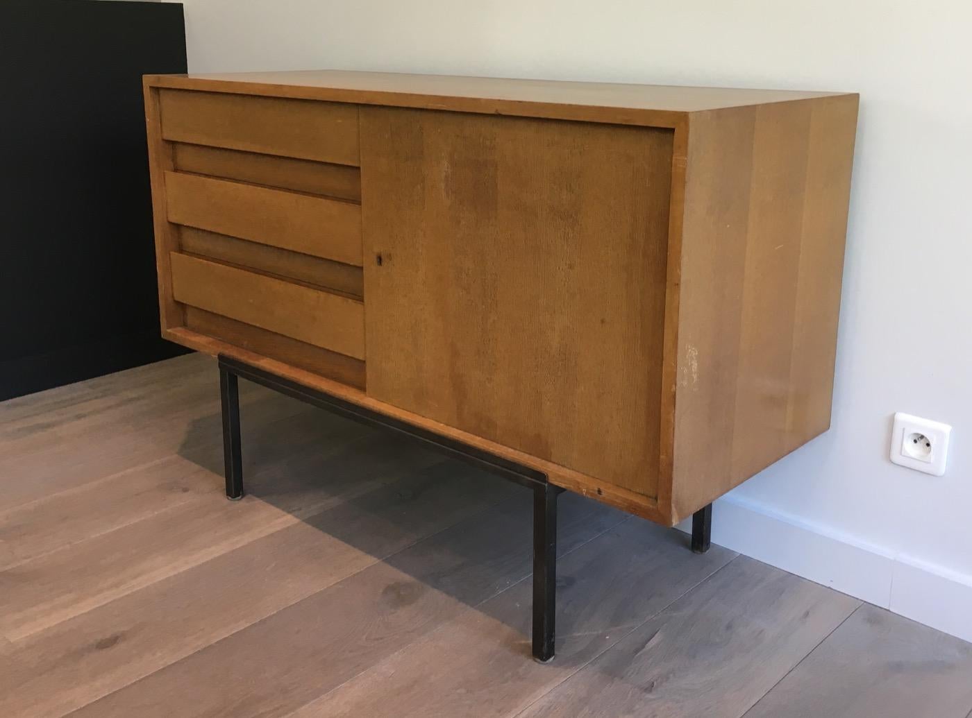 This nice sideboard is made of oak on a modernist lacquered still base. It has a door on its left part on three drawers on the right part. This is a French work, circa 1950.
 