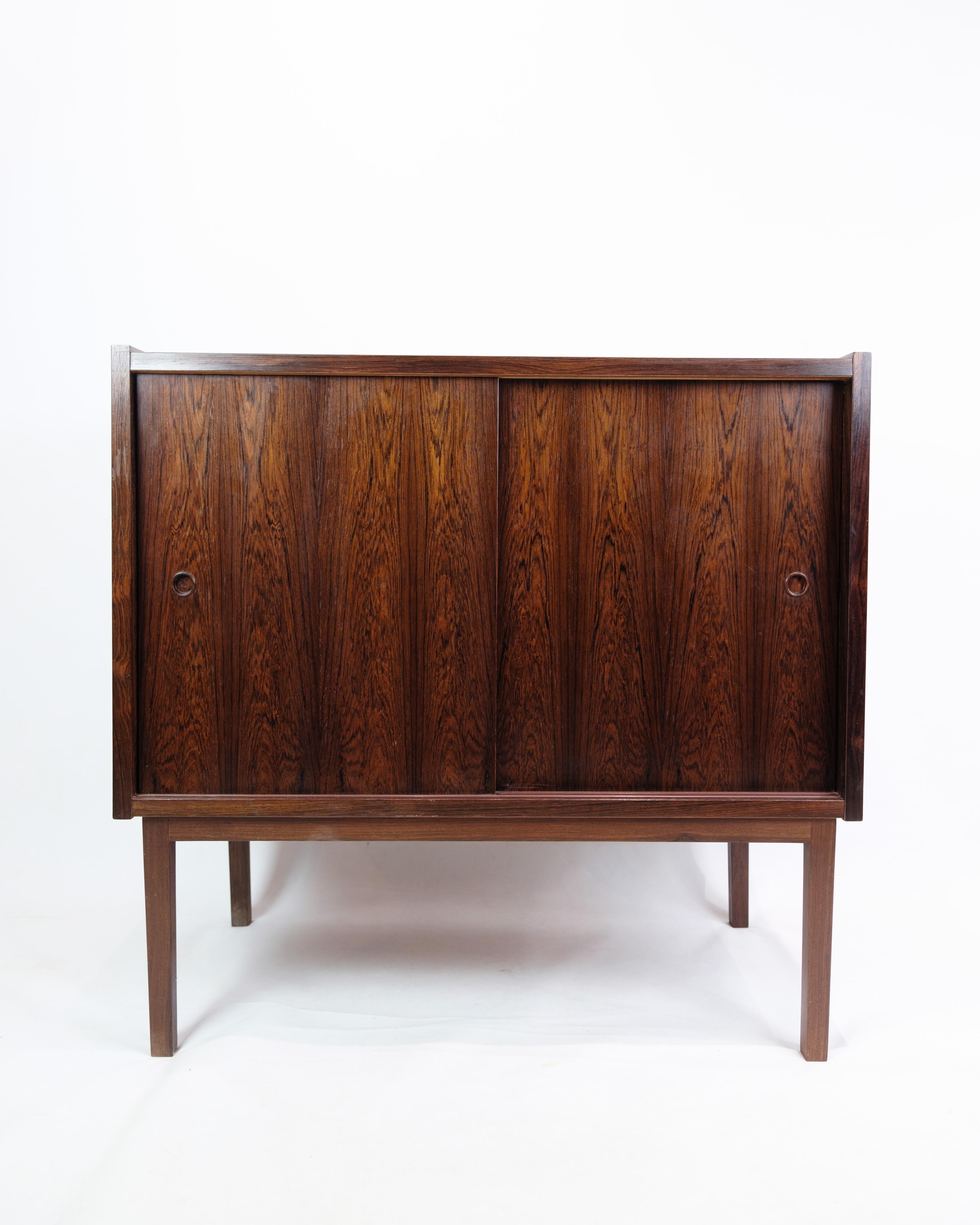 The small rosewood sideboard, of Danish design and from the 1960s, represents an era of stylish and functional furniture design. The rosewood, with its characteristic dark color and beautiful veins, gives the sideboard a unique and luxurious