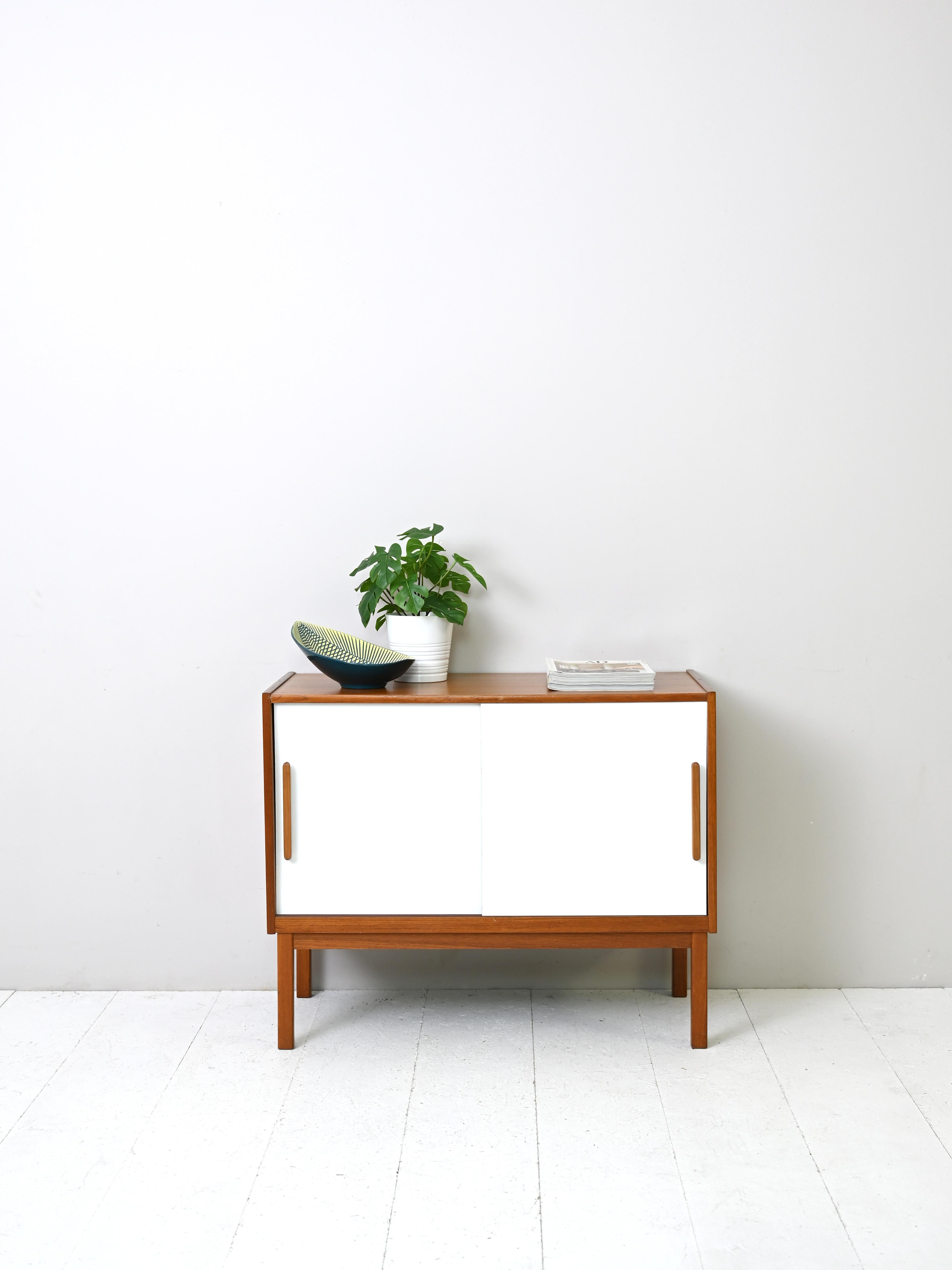 Scandinavian cabinet with sliding doors painted white.
Small original teak cabinet from the 1960s.
A simple and functional piece of furniture with a minimalist design, typical Scandinavian. Consisting of a compartment
storage unit with sliding