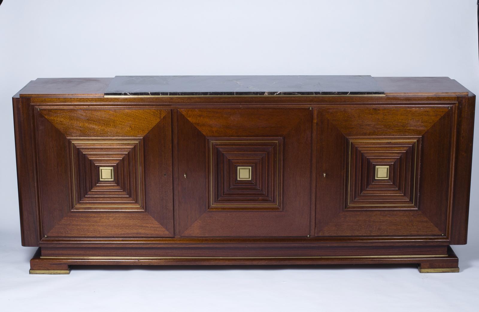 Buffet in solid wood and panels in wood veneer.
Three molded doors with highlights in gilded bronze.
Recessed base with four heels of angles in gilded bronze.
Top partially covered with veined black marble, highlighted with a bronze rod.
 