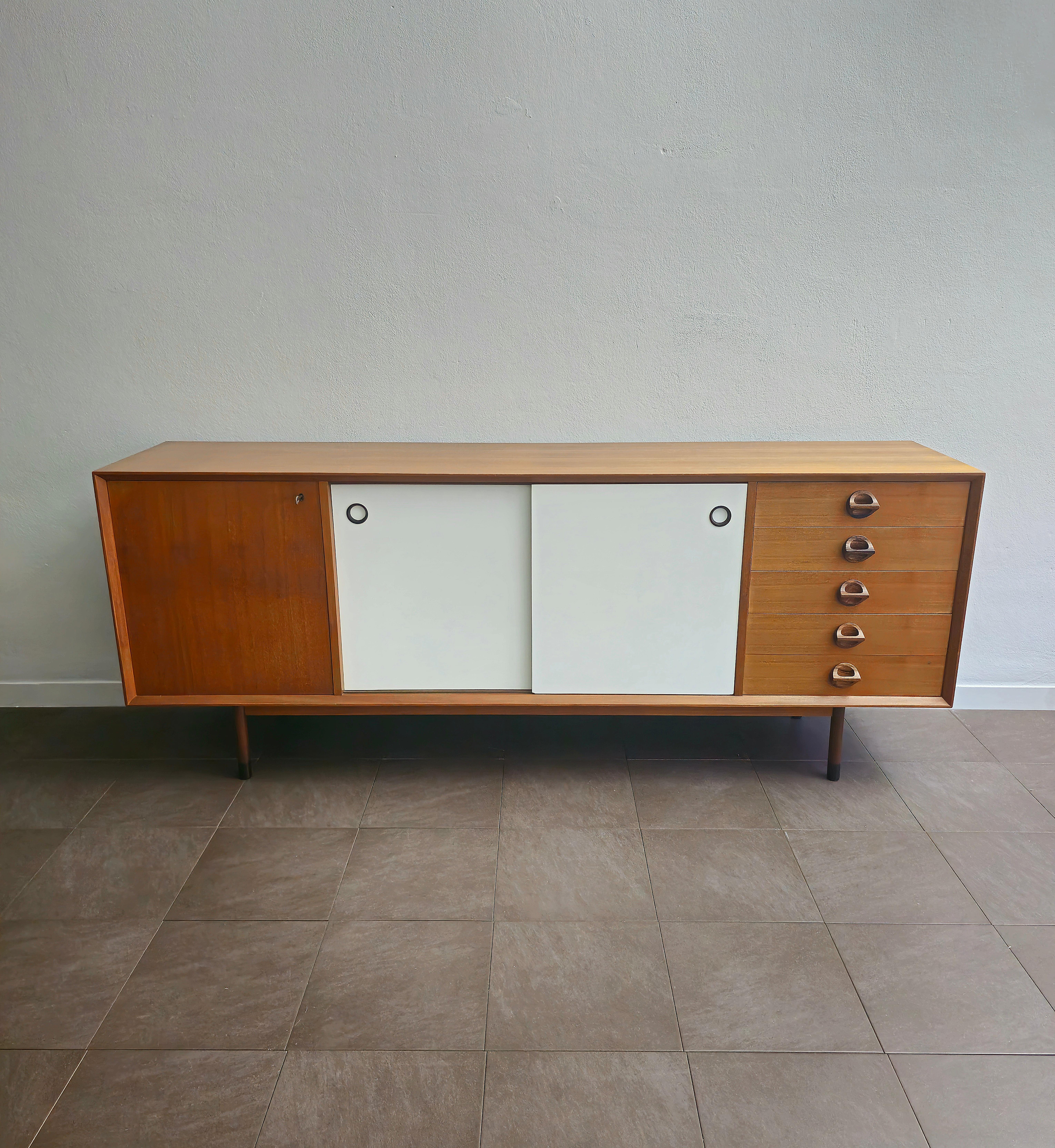 Sideboard of considerable size made of solid wood and teak with a door on the left with a shelf inside, in the center it has 2 sliding doors with the particularity of being reversible, inside we find two more shelves and finally on the right side it