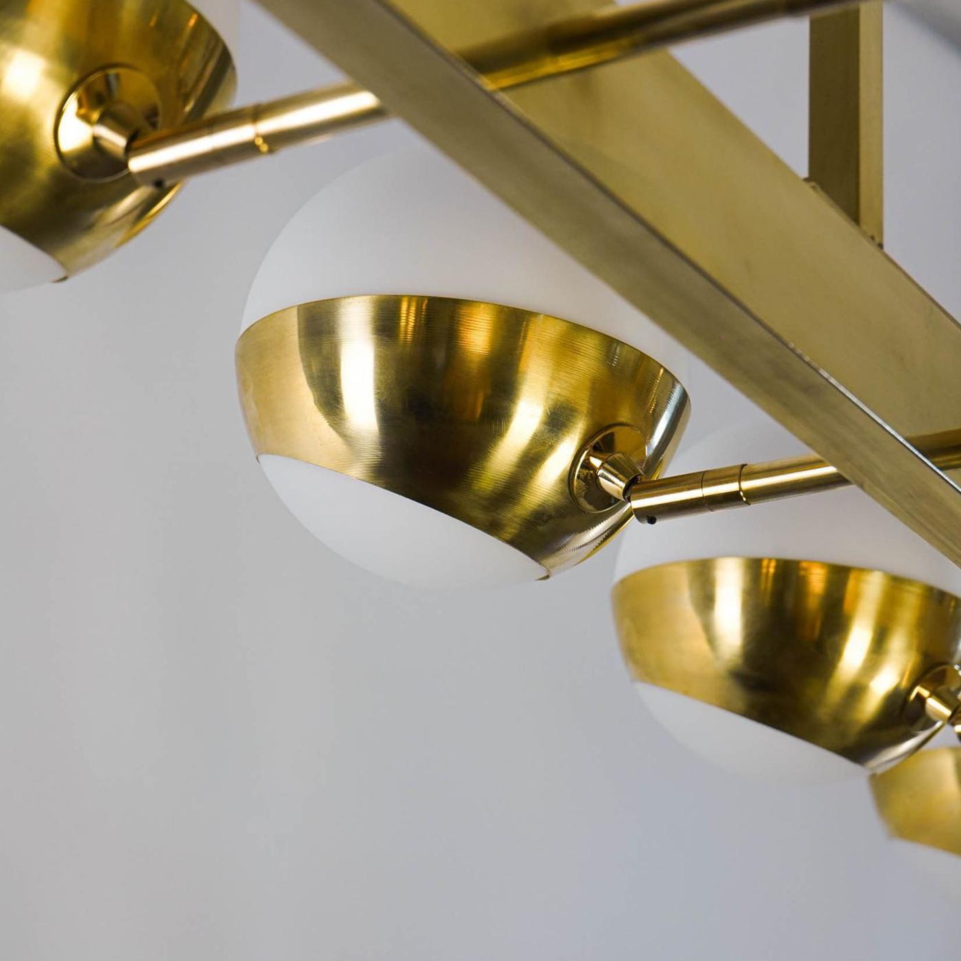 This chandelier features two rows of five shades, perfect for dining tables or rectangular islands. Inspired by 1950s Italian mid-century modern studios like Arteluce and Stilnovo, it combines style and functionality. The hand-finished brass shades