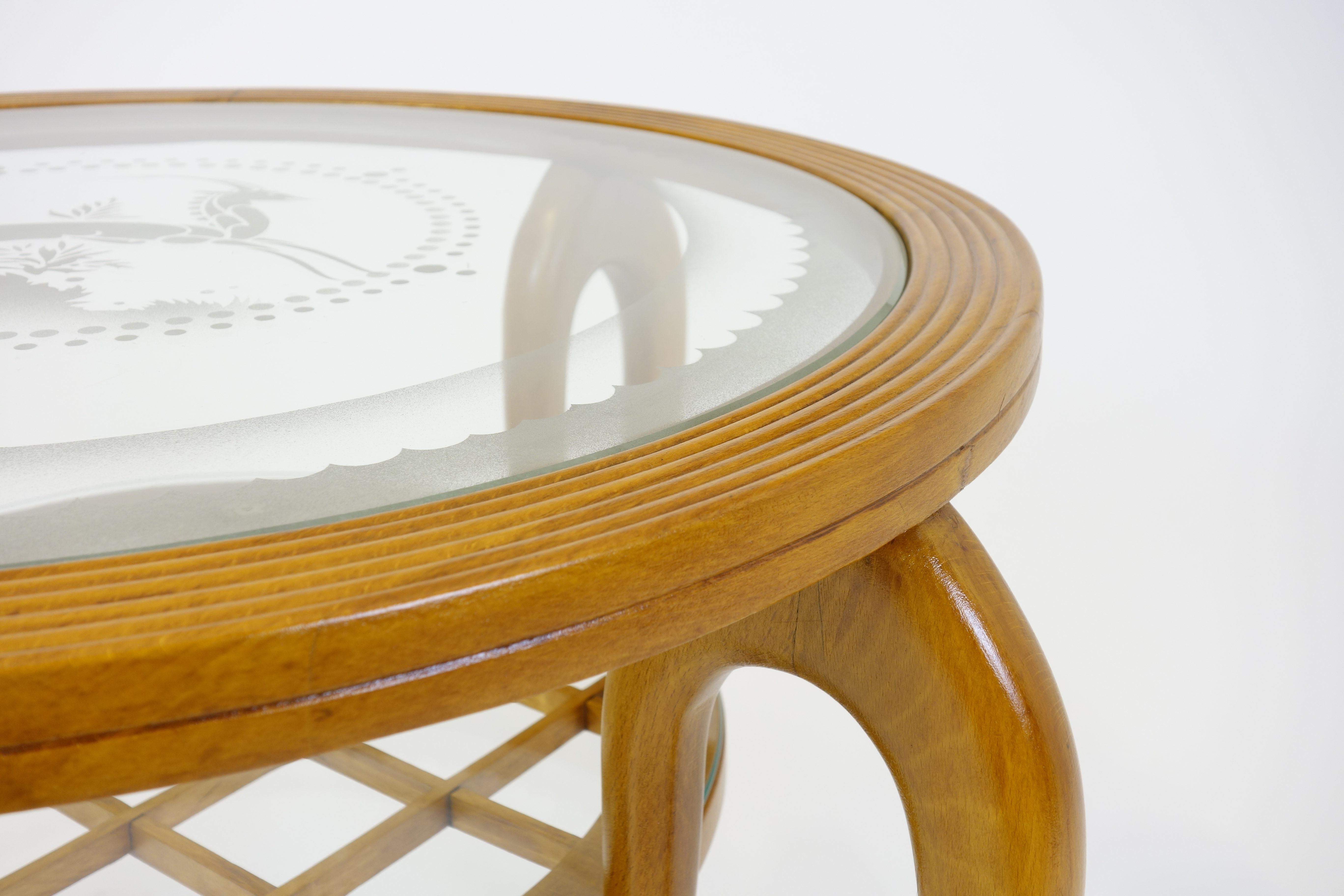 A side table from the 1940s in the manner of the Italian architect and star designer Gio Ponti. The furniture is made of pear wood with two circular original glass tops. The larger one is etched with a deer as its central motif surrounded by