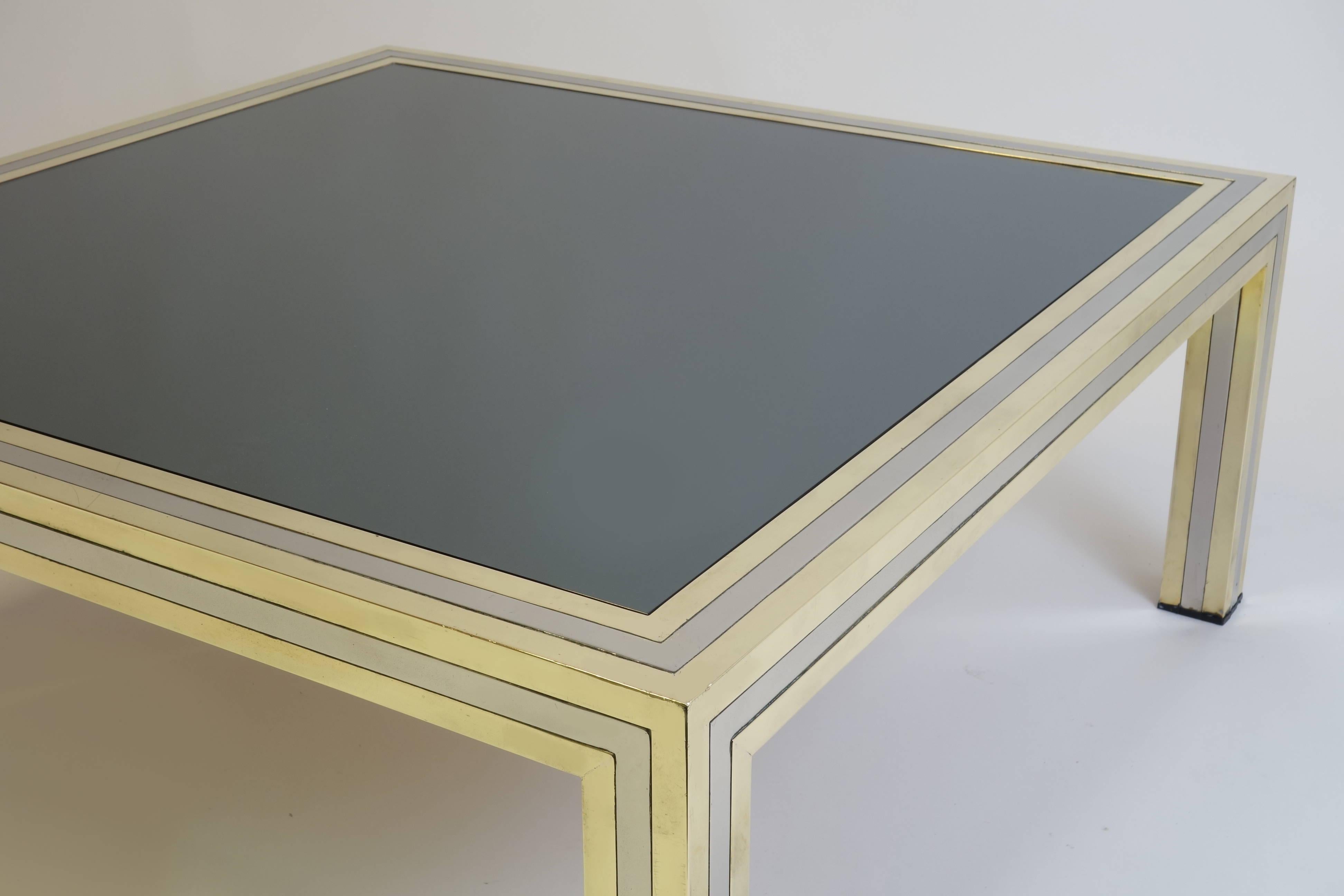 An impressive coffee table styled by the Italian designer Romeo Rega manufactured in the mid-1970s. The frame made of nickel-plated metal and brass carries its top of tinted mirror glass. Its gold or silver sequence as an expressive statement