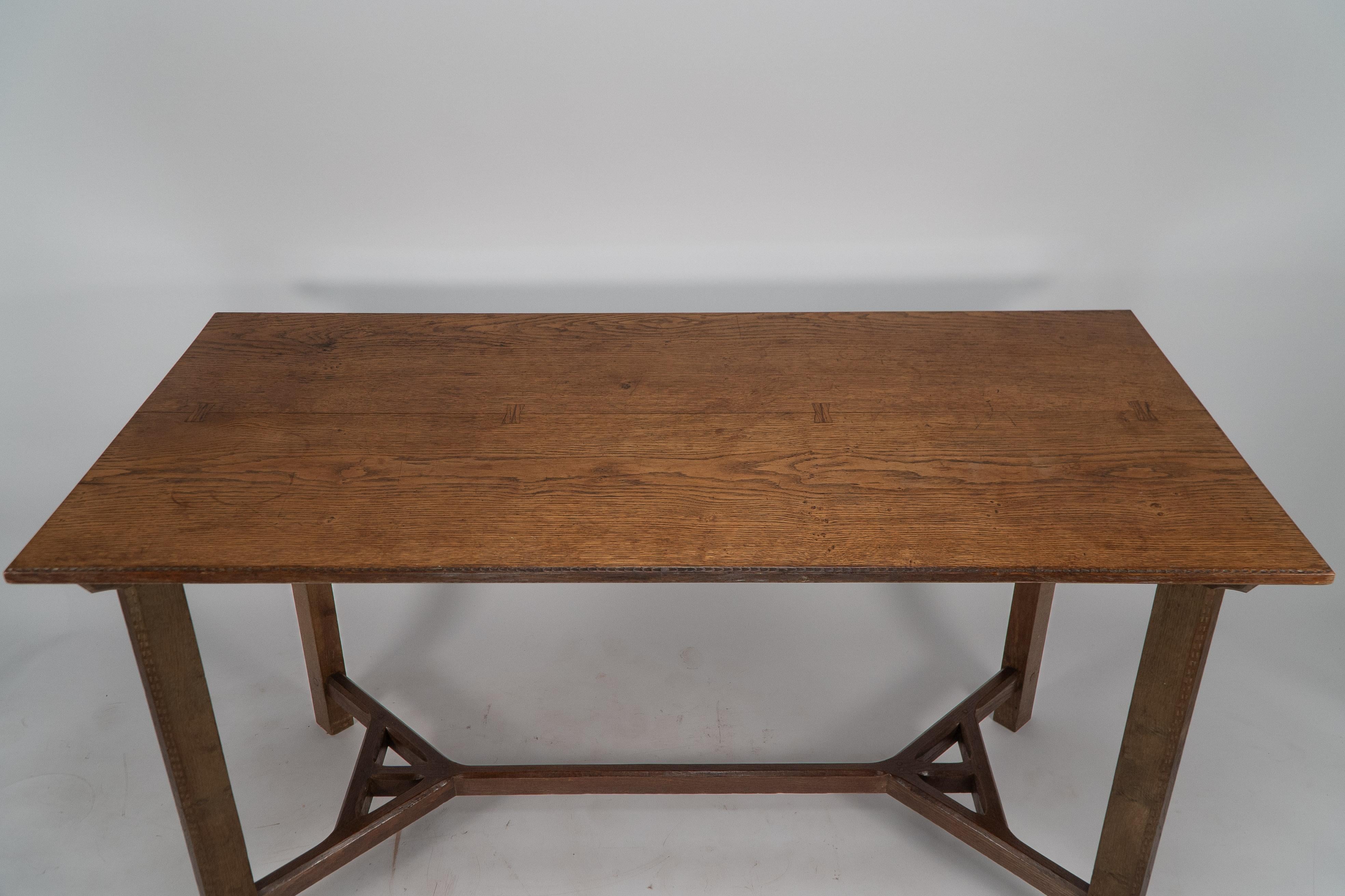 Sidney Barnsley attributed. A rare Cotswold School Arts and Crafts hayrake oak dining table with a rare double use of the hayrake stretcher design, one to the base uniting each leg and again identically repeated underneath the table top, where it