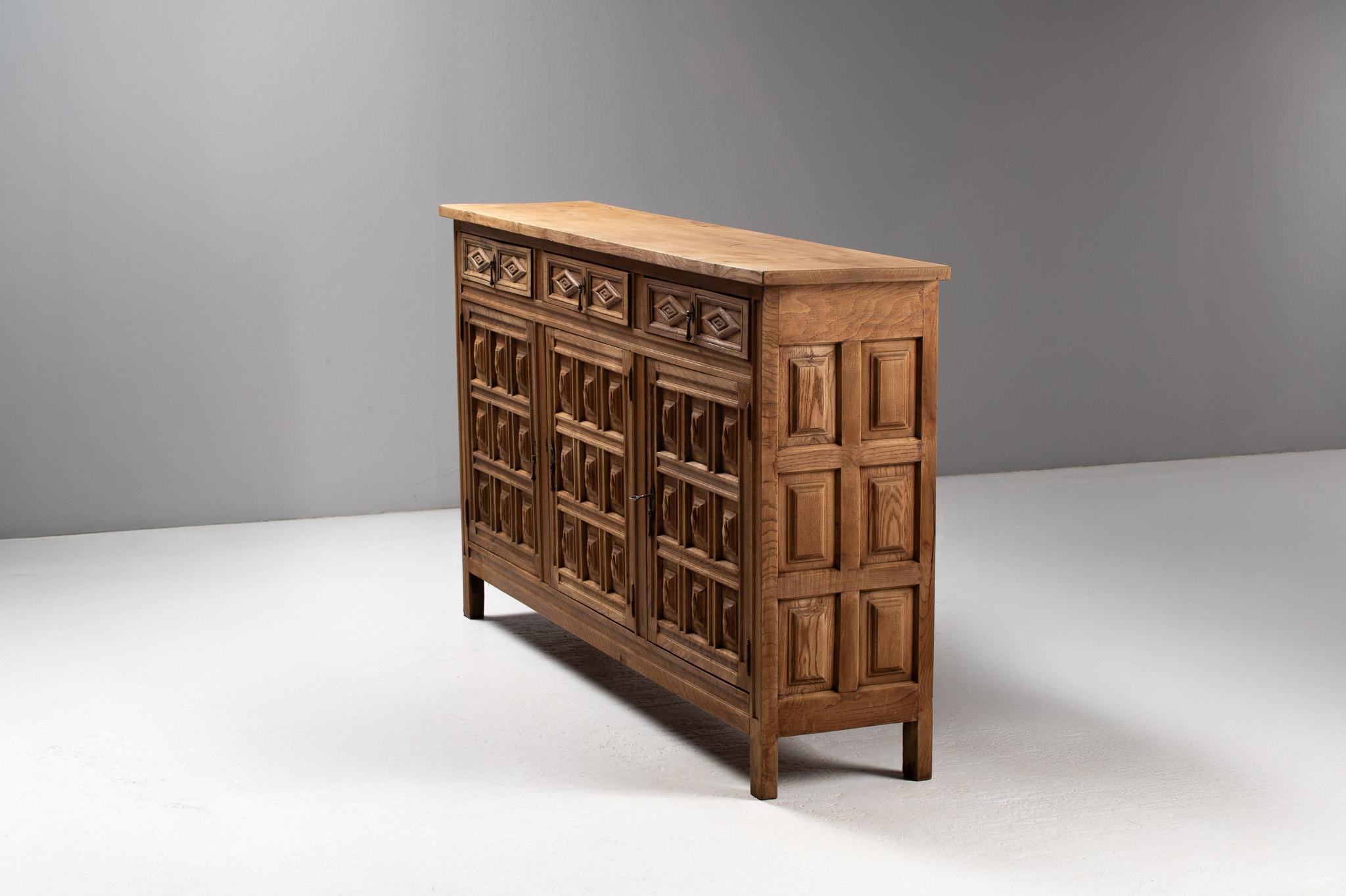 A rare gesture of ornamental restraint and regional craft, this Spanish buffet from the 1940s distills centuries of vernacular design into an unusually narrow architectural volume. Just 14.96 inch in depth, it was likely conceived for a corridor or