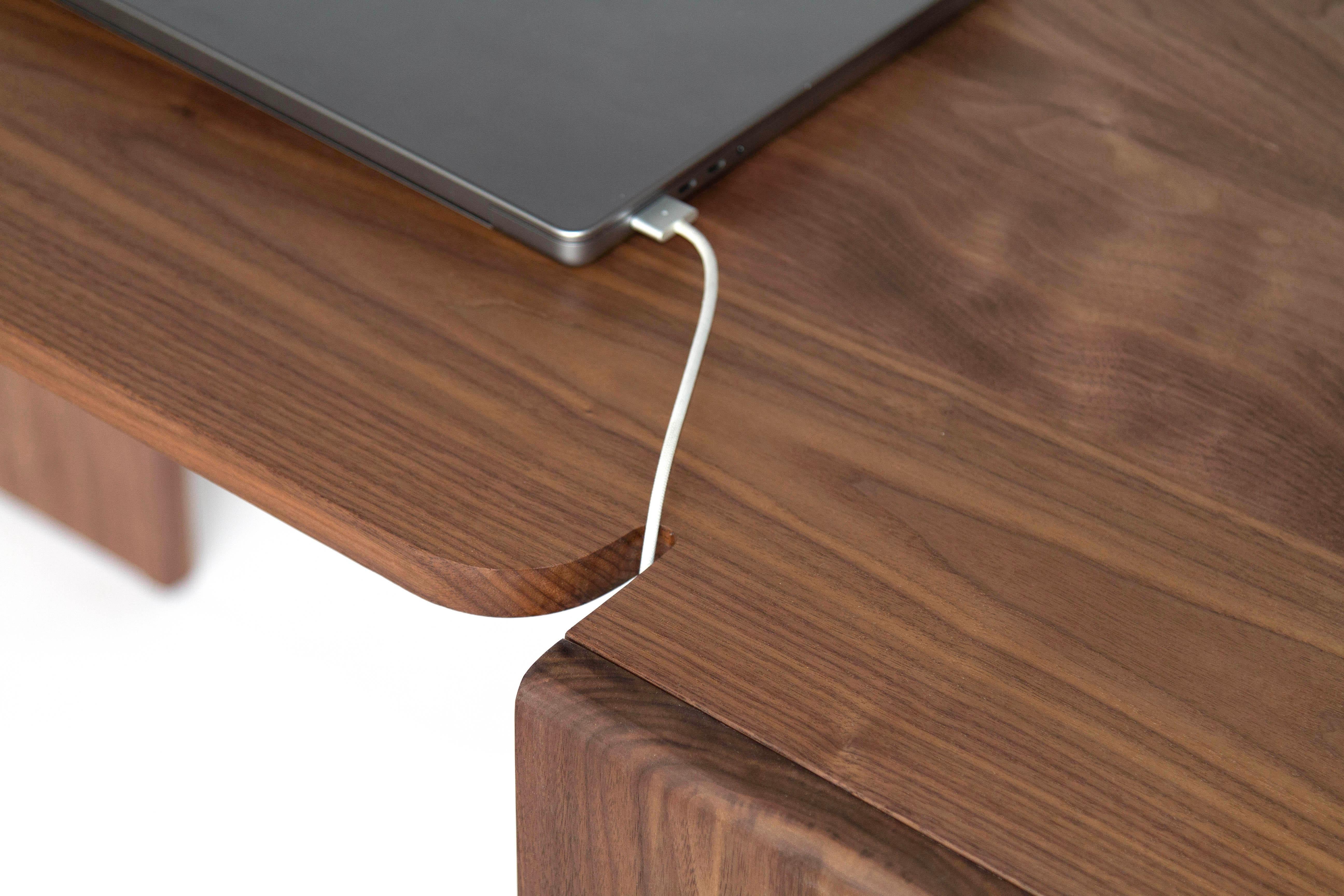 Minimalist desk with surprising details like grooves for cables and different-width legs. 