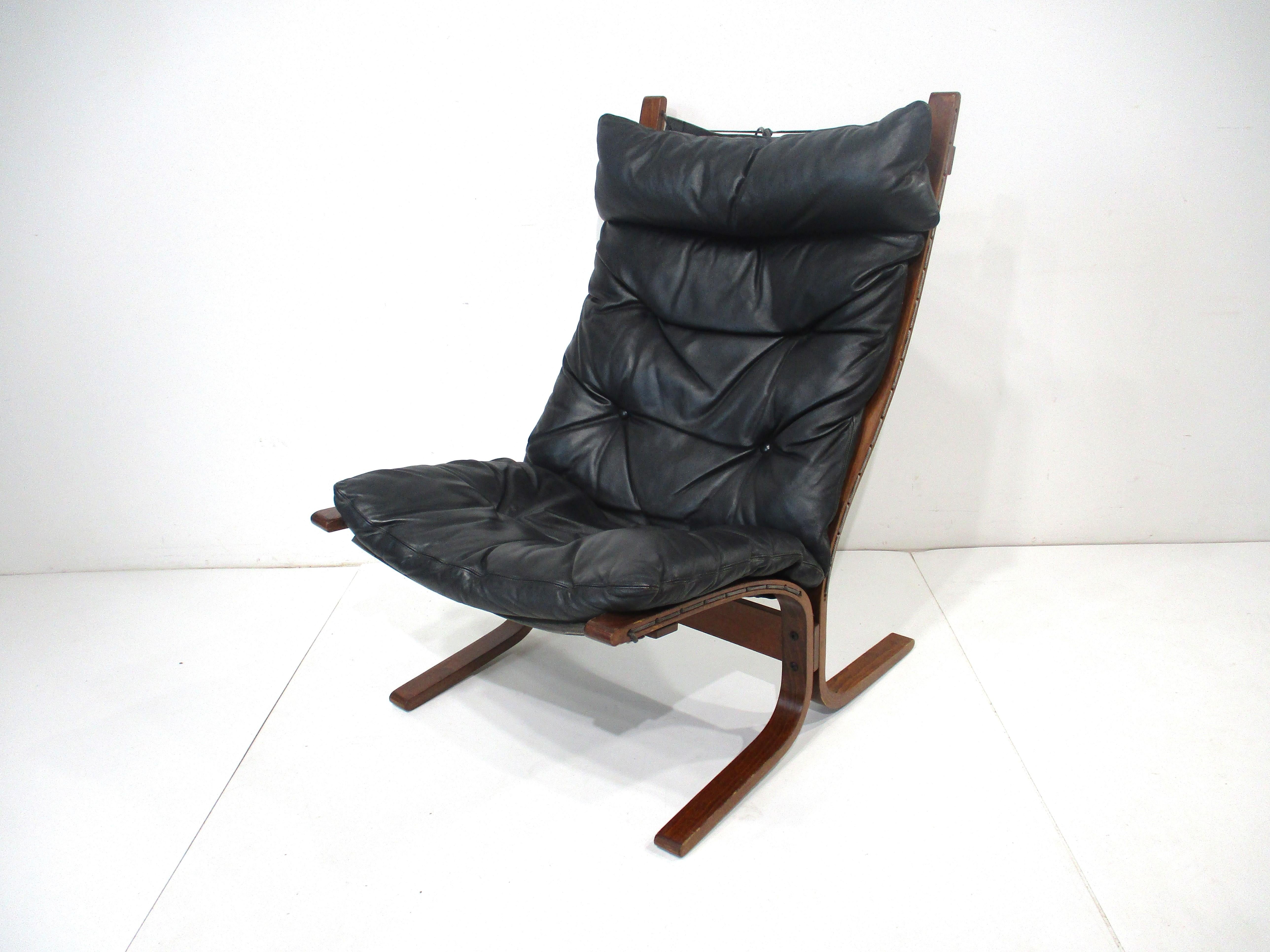 A black leather and rosewood toned bentwood cantilevered Siesta lounge chair with canvas sling styled back for comfort . A simple design coming from the Mid Century Danish modern period designed by Ingmar Relling for the Westnofa furniture company