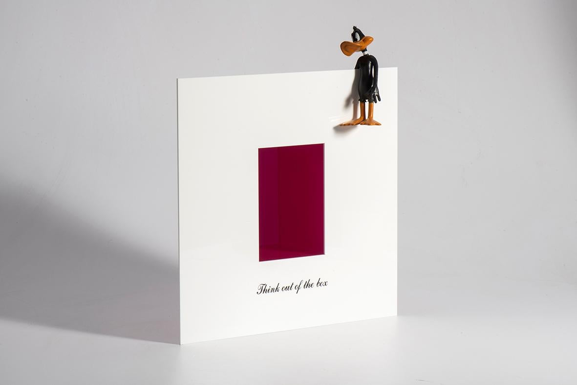 A unique artwork crafted from Plexiglas, featuring an engraved phrase that adds depth and meaning. Perched atop the artwork’s frame is a small figurine, creating a playful yet thought-provoking contrast between words and form. For wall installation
