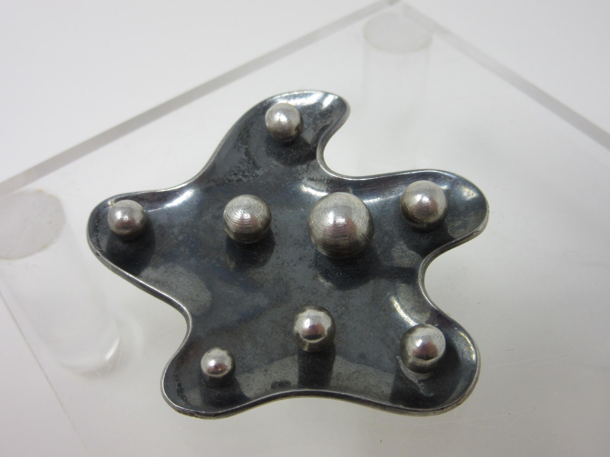 A well crafted sterling silver brooch pendent with amoeba shaped design having 8 silver balls of varying sizes to the front. The back round has been oxidized by the artist and the edges polished to accentuate the the piece, works by a group of