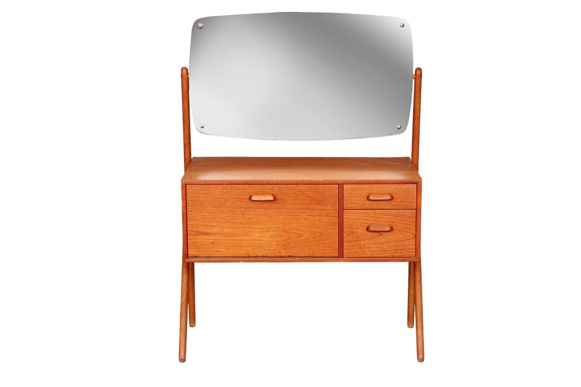 A 1960’s Y-leg vanity with mirror made of teak. Designed by Sigfred Omann and manufactured by Olholm Mobelfabrik of Denmark. A fall front cabinet to the left and two dovetailed drawers to the right open with recessed handles.

W27” x D14.5” x Height