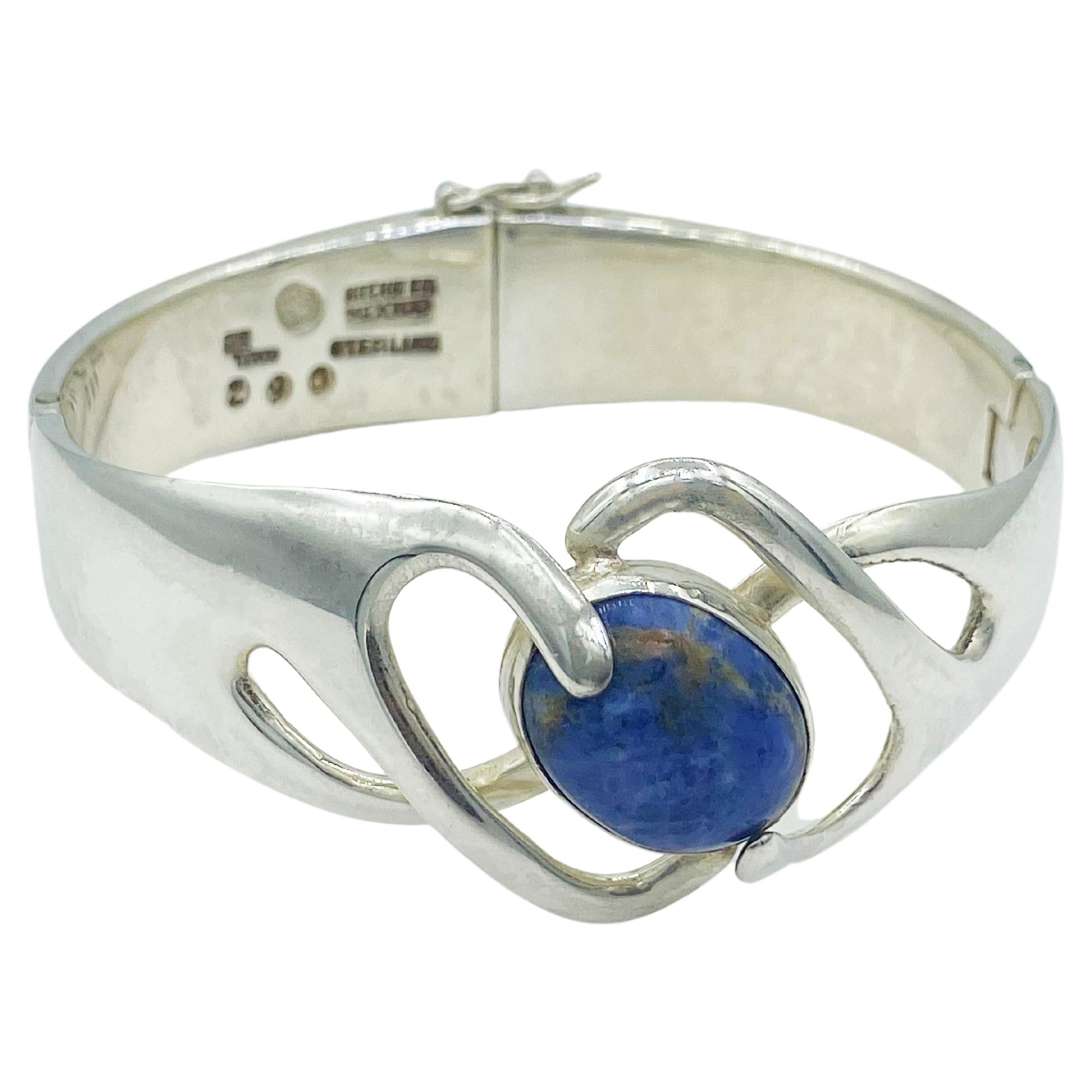 Beautiful vintage Sterling Silver and Sodalite hinged bracelet from Taxco Mexico master silversmith, Sigi Pineda. The centerpiece of the bracelet is a sodalite oval cabochon bezel-set at an angle. The royal blue stone has swirls of white along with