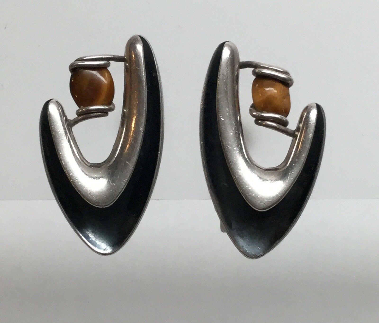 Sigi Pineda Taxco sterling silver boomerang screw back earrings with Tiger's eye #34.

Marked: Sigi, TASCO, Eagle 3, STERLING SILVER TAXCO (in circle), 34.

Measures: 1 1/4
