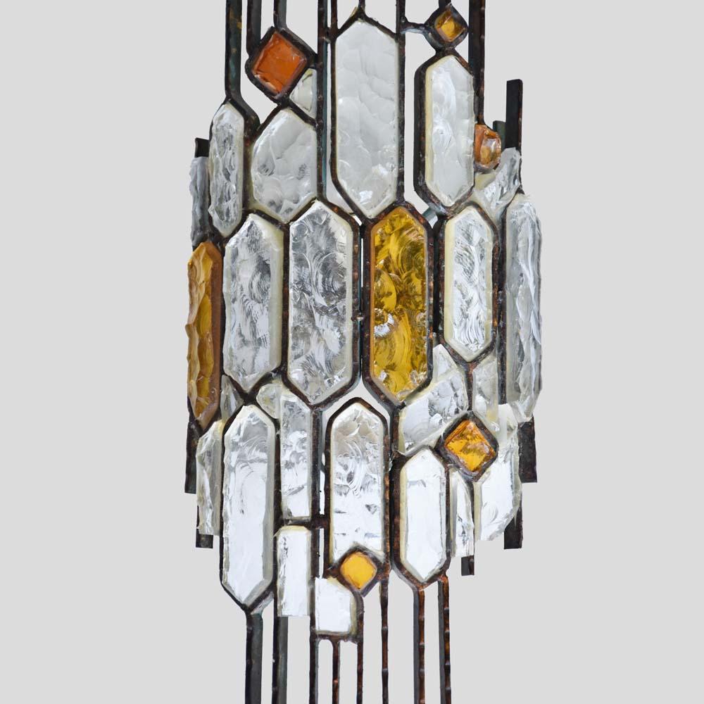 This wall light is a stunning artistic sconce. It features a brown enamelled wrought iron structure with rock-shaped clear and amber hammered glass. Designed by Longobard in the 1970s, this Italian wall light has a touch of Art Nouveau style while