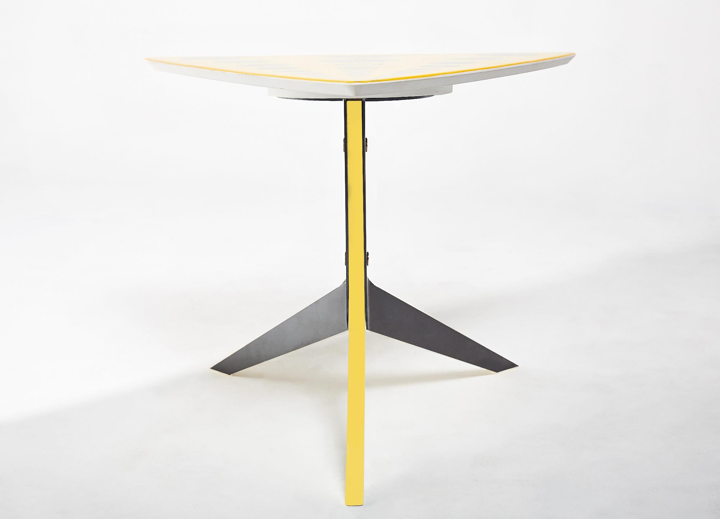 Signal table with a top featuring a design of fruitwood end-grain embedded in Yellow rain coat resin. Sculptural base consists of two black steel legs paired with a single yellow rain coat resin leg. 

Size: 23
