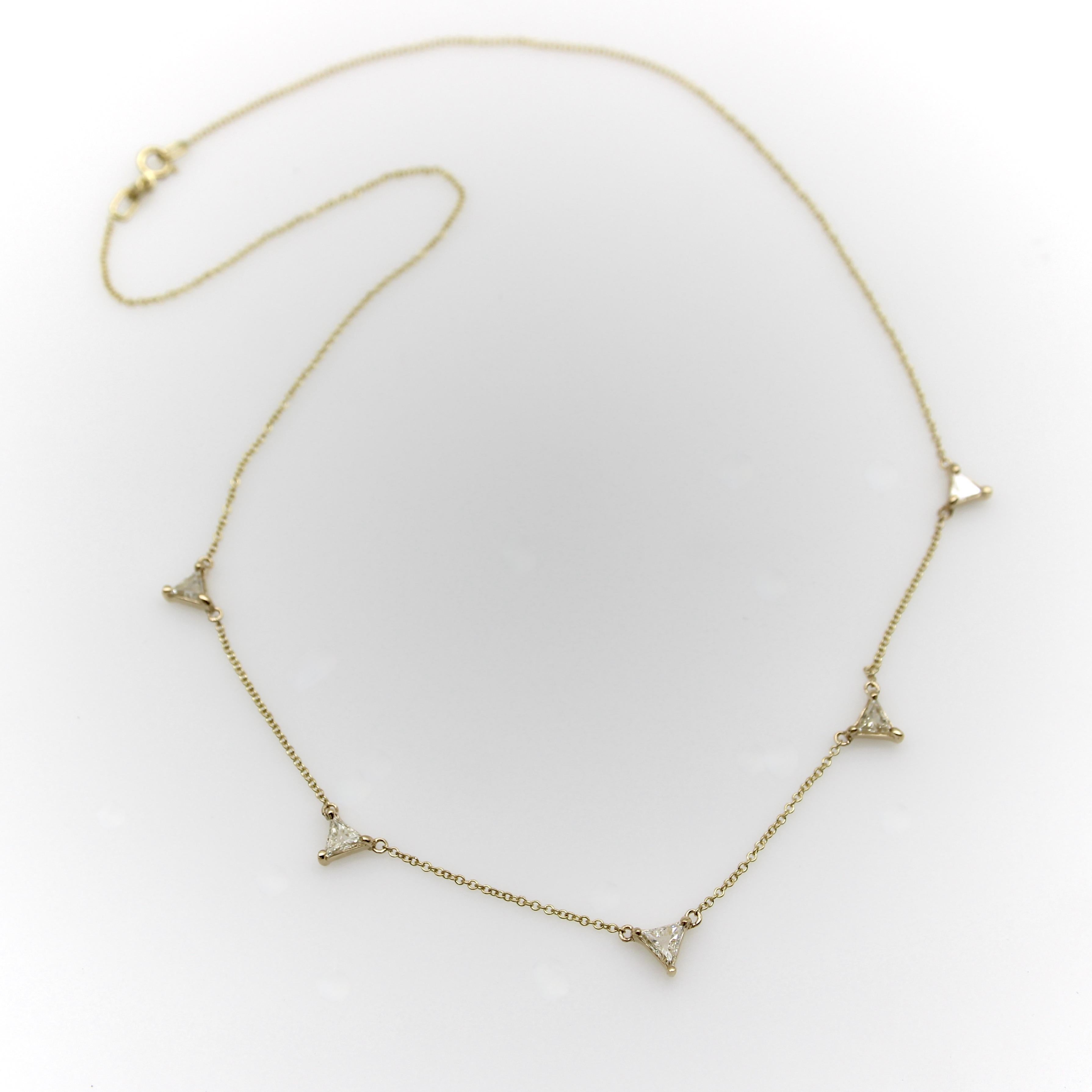 Este collar de oro de 14 quilates y diamantes forma parte de la colección Kirsten's Corner Signature. Presenta cinco diamantes talla trillón sujetos en monturas triangulares sobre una delicada cadena de oro de 14k. Cada diamante se conecta a la