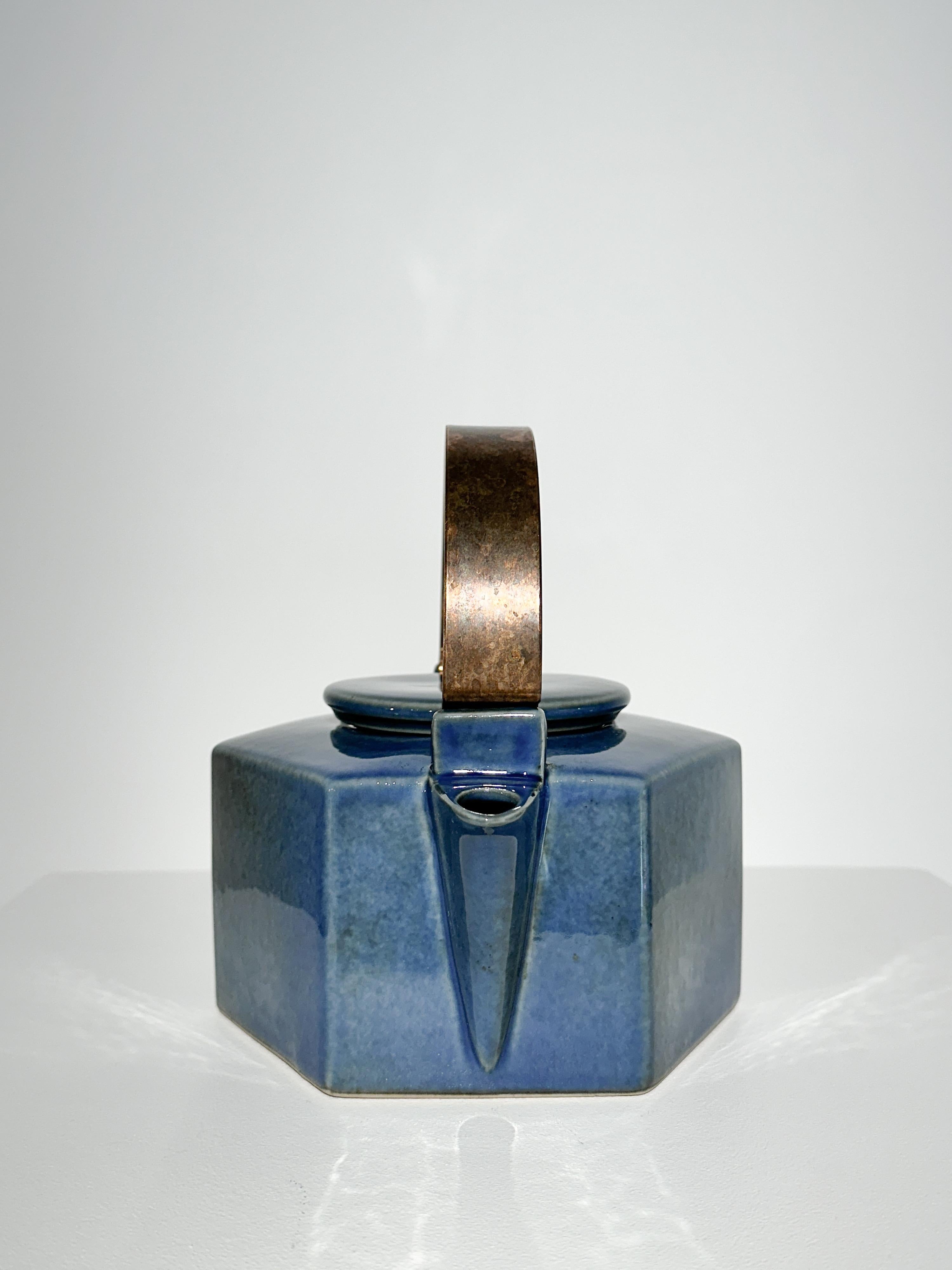 Théière de forme hexagonale de la designer suédoise Signe Persson-Melin, modèle n° 225 pour Rörstrand Suède, années 1970.

Grès artisanal avec une belle glaçure bleue, poignée en cuivre massif.

Très bon état, cuivre patiné pouvant être poli sur