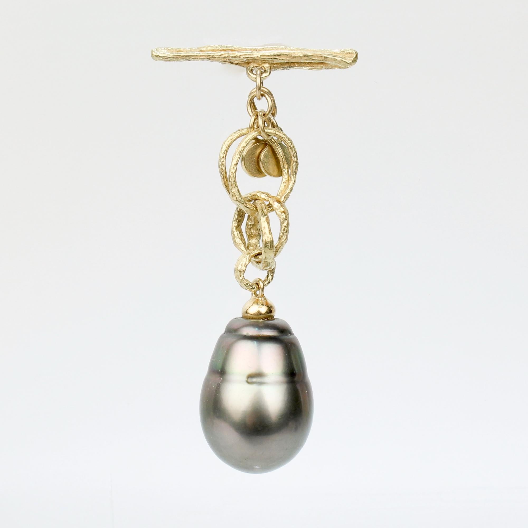 Bouton de revers ou porte-bonheur en or fin et perle de Tahiti baroque.

En or 18k.

Il s'agit d'une barre à bascule en or reliée à plusieurs anneaux en or entrelacés et se terminant par une grande perle de Tahiti de forme baroque.

Tout simplement
